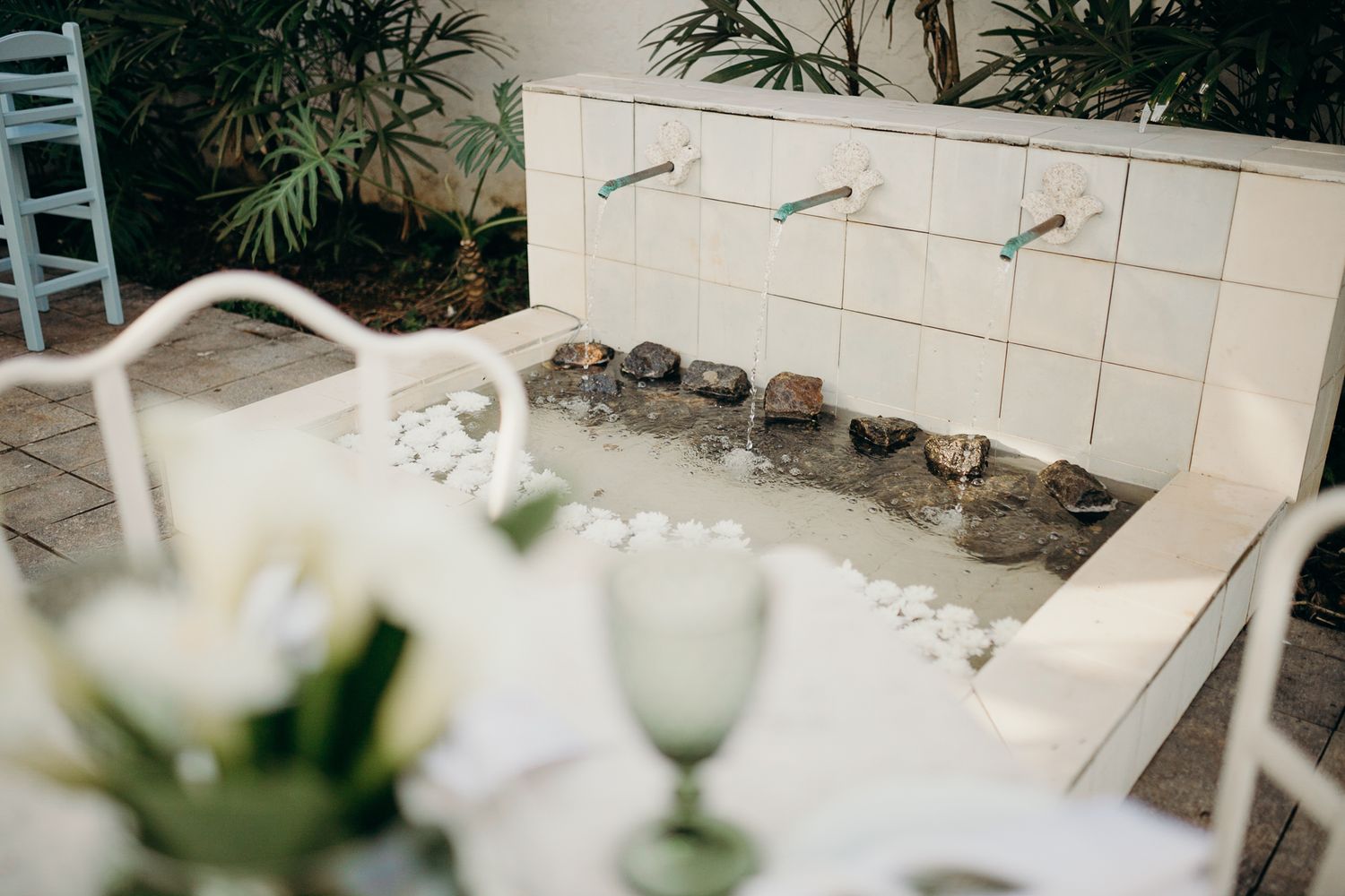 White chairs and floral arrangements set up for an outdoor garden event.
