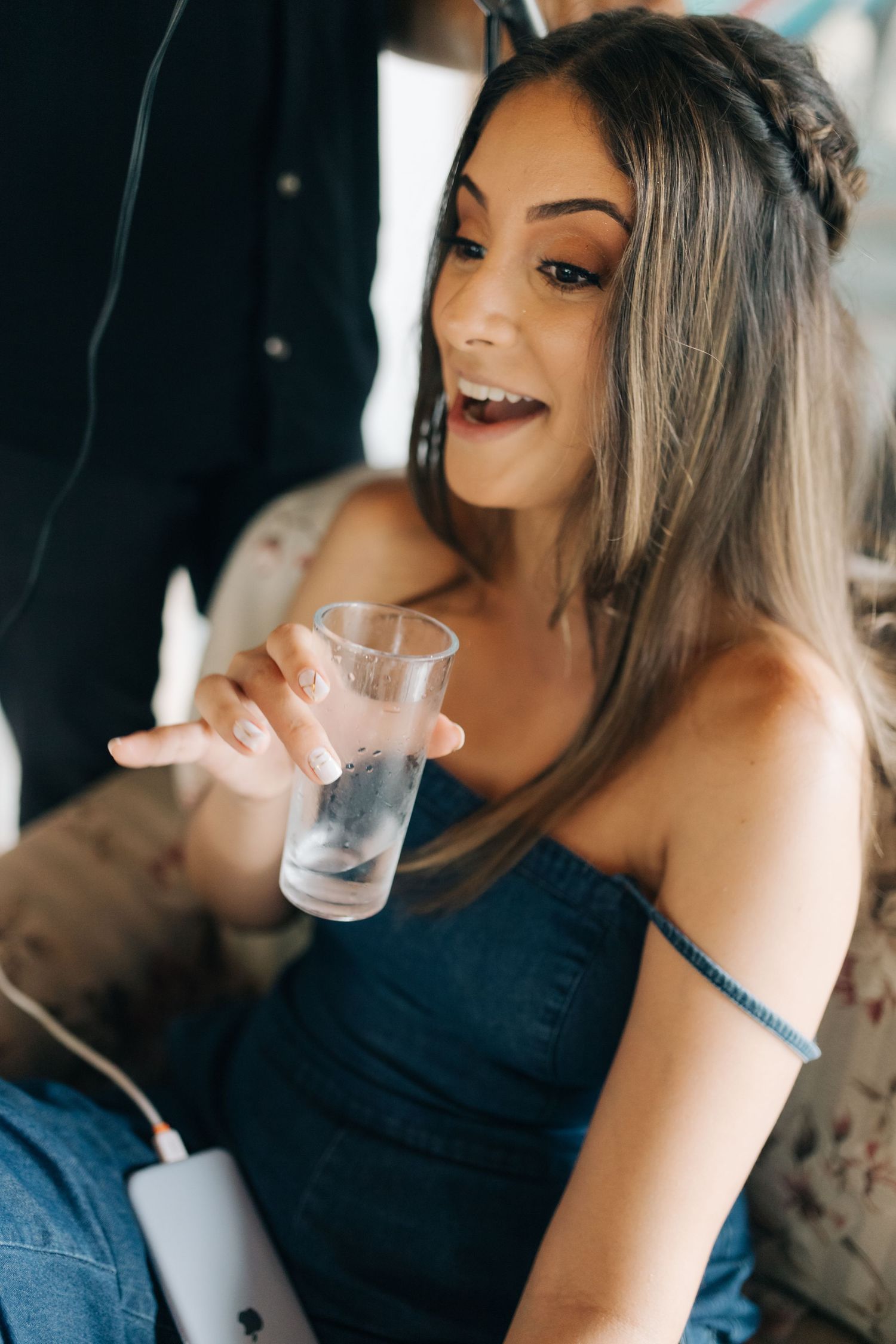 Woman in blue dress holding glass at social gathering.
