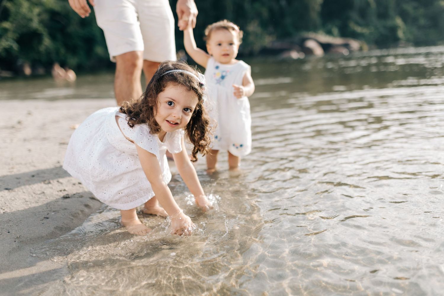 Children playing and splashing in shallow water at the edge of a lake.