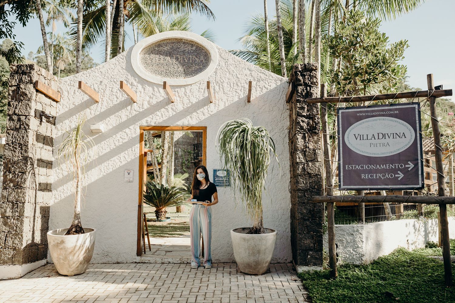 Elegant white archway entrance to Villa Capponi with potted plants and palm trees in background.