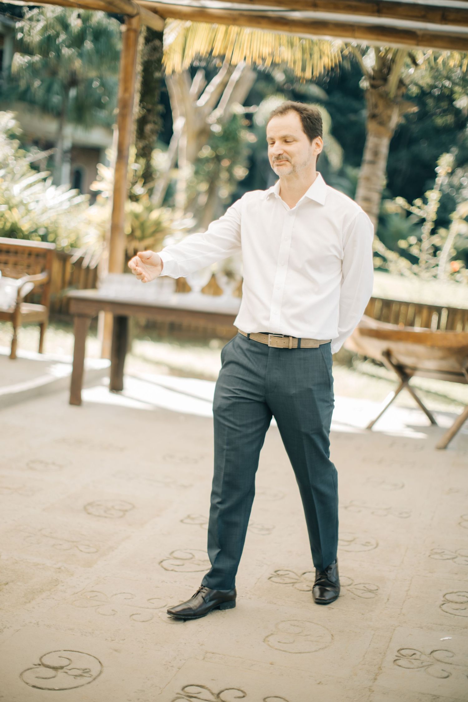 A guest in formal attire stands on a covered patio with decorative floor patterns.