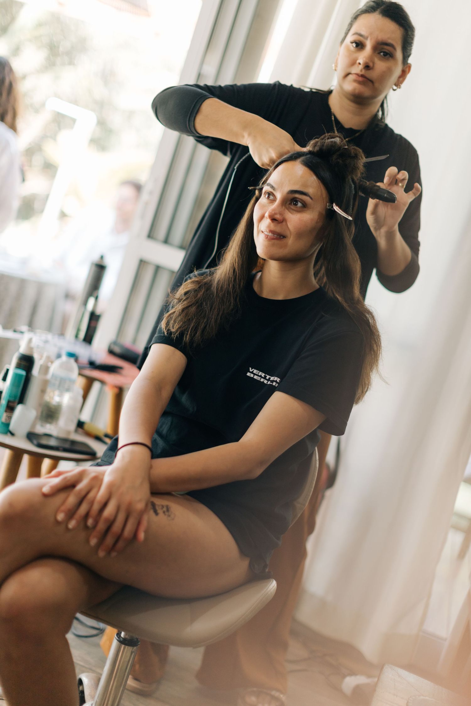 Stylists in black t-shirts work on clients in a modern salon setting.