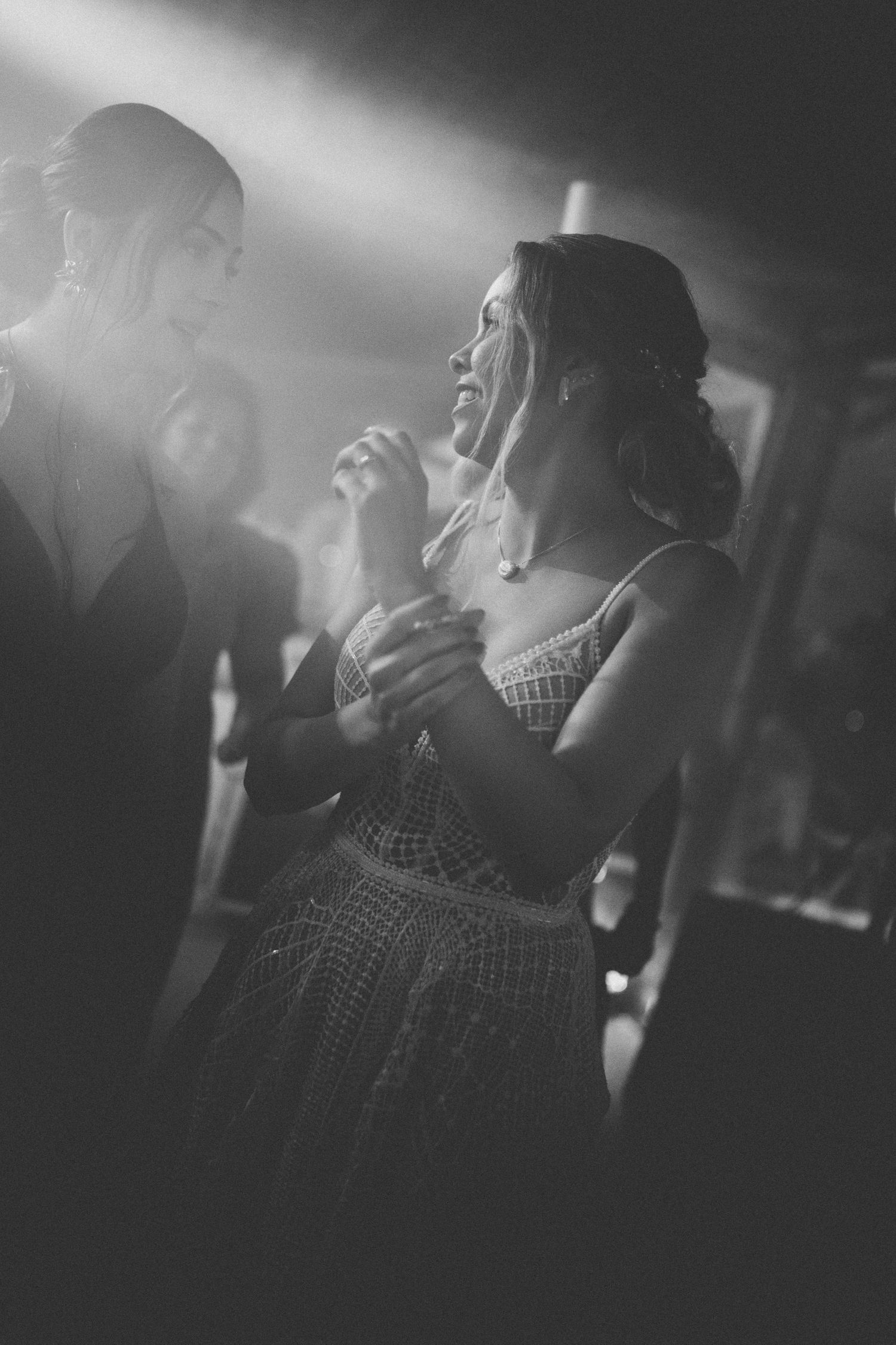 Artistic black and white shot of guests dancing at a dimly lit wedding reception.