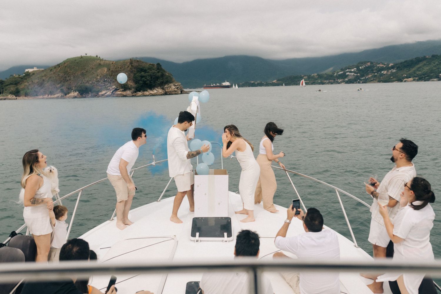 Group enjoying leisure time on yacht deck with mountain harbor scenery.