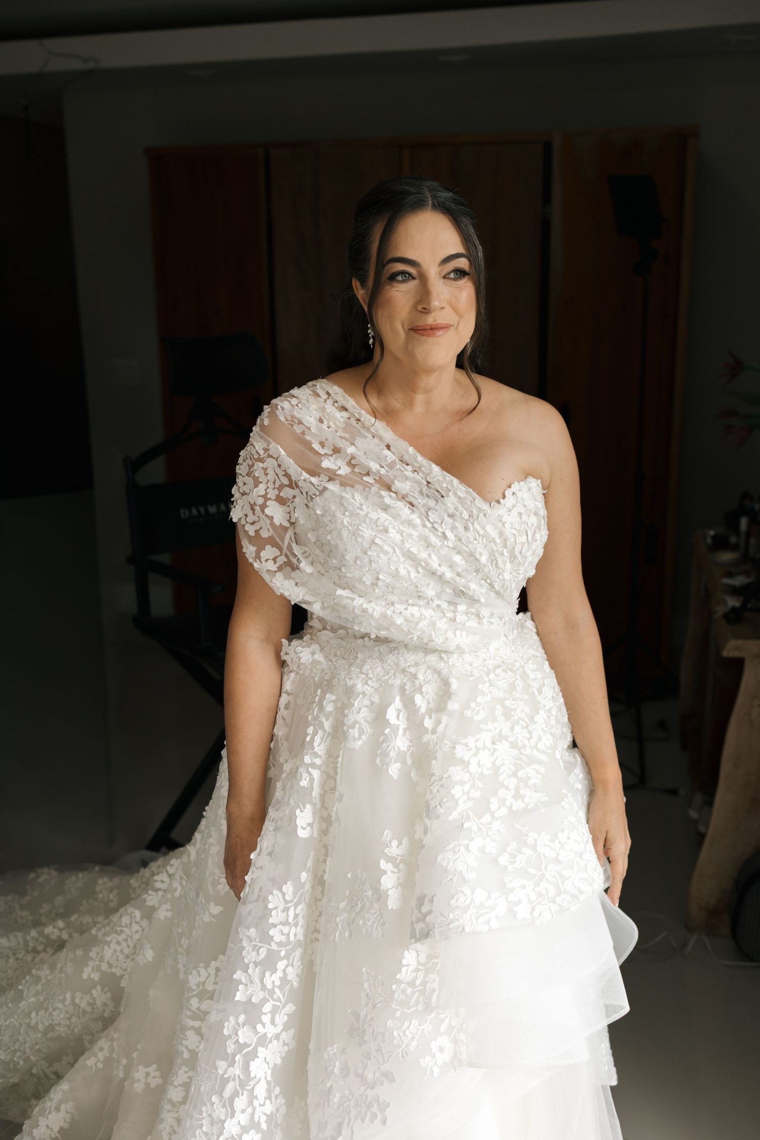 A close-up view of a white lace wedding dress with delicate beading and off-shoulder details.
