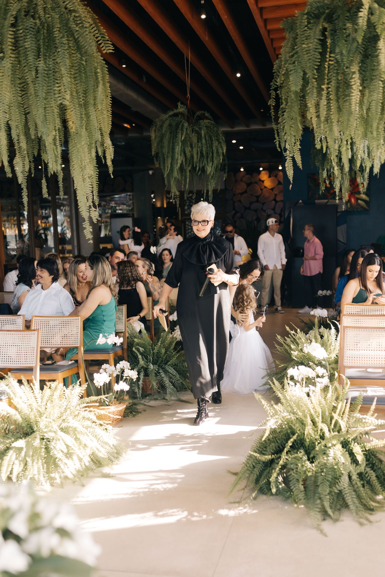 Wedding aisle decorated with hanging plants and white flowers in modern venue.