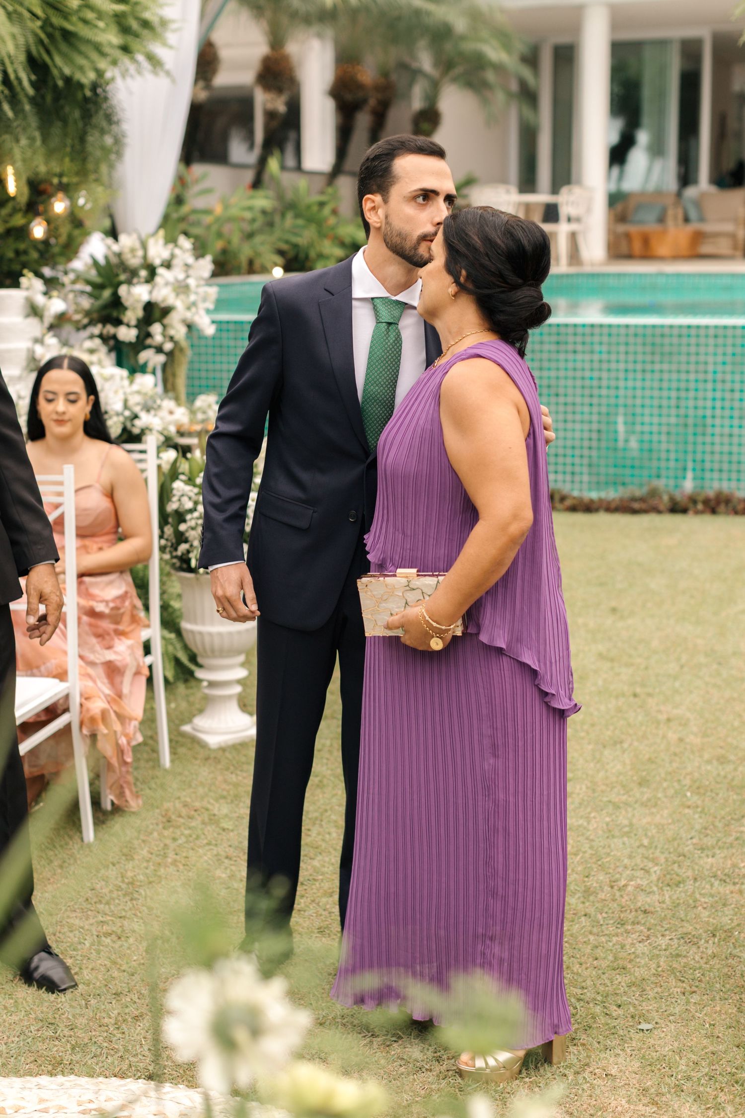 Couple in purple dress and dark suit sharing intimate moment at outdoor event.