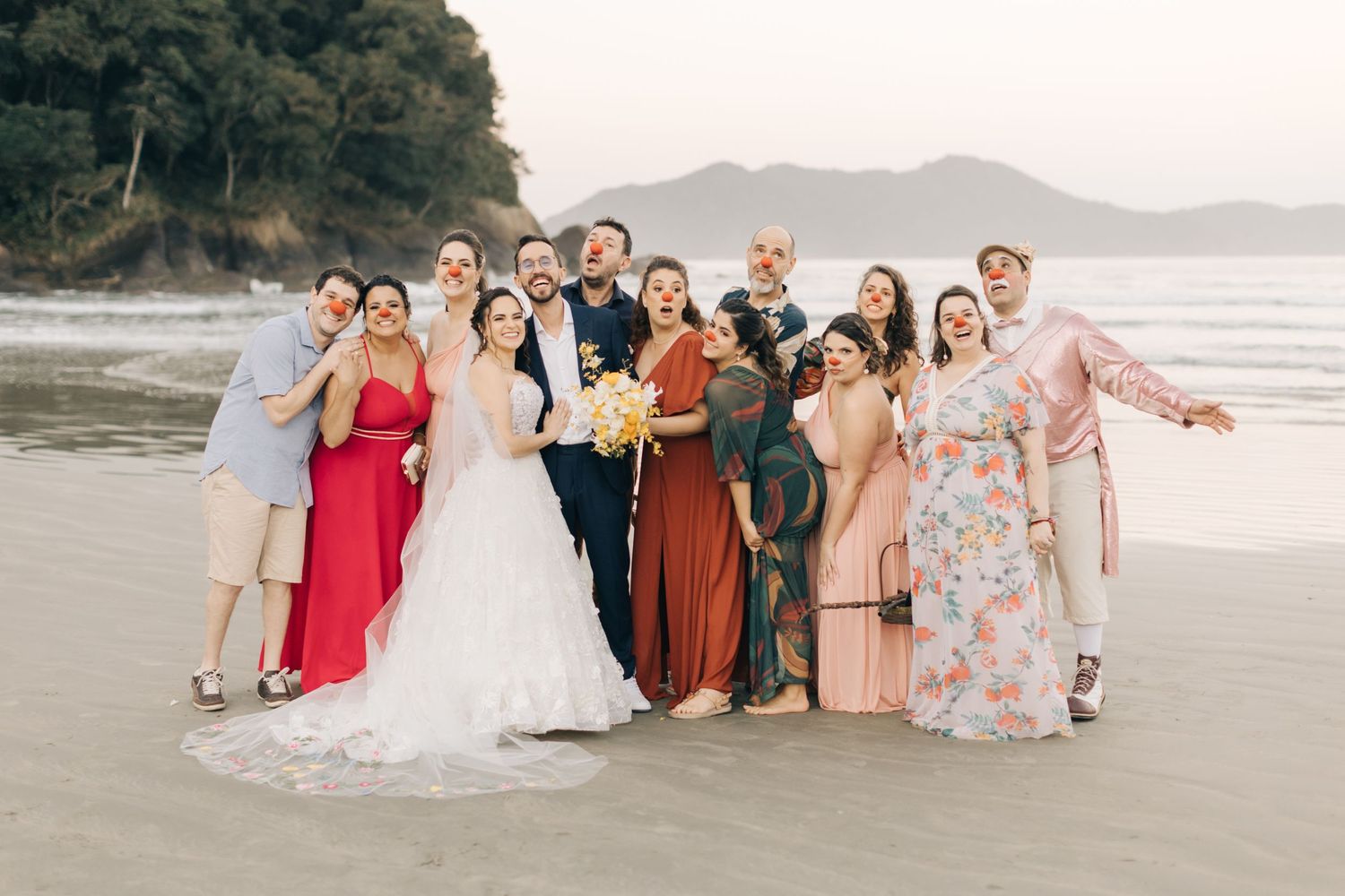 Wedding party gathered on the beach for group photos at sunset.