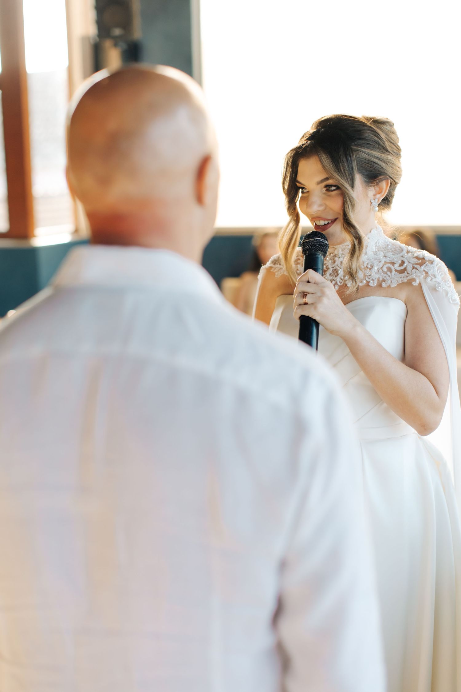 A close-up shot of a bride speaking into a microphone during wedding vows.