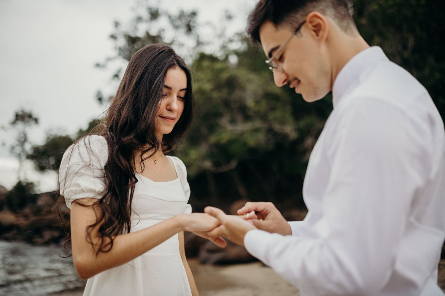 Ring exchange moment captured during beach proposal.