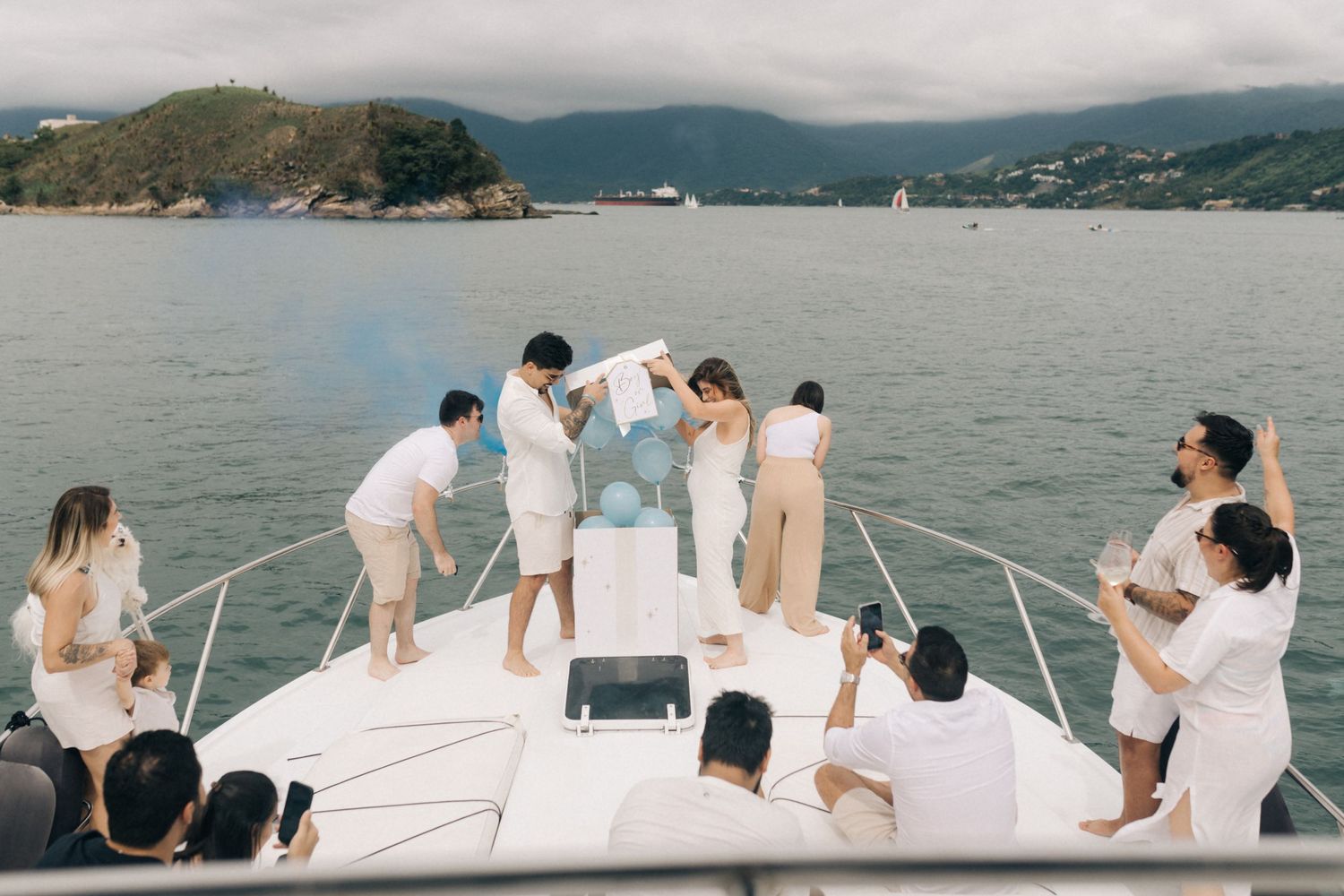 White yacht deck filled with people enjoying a scenic mountain bay cruise.