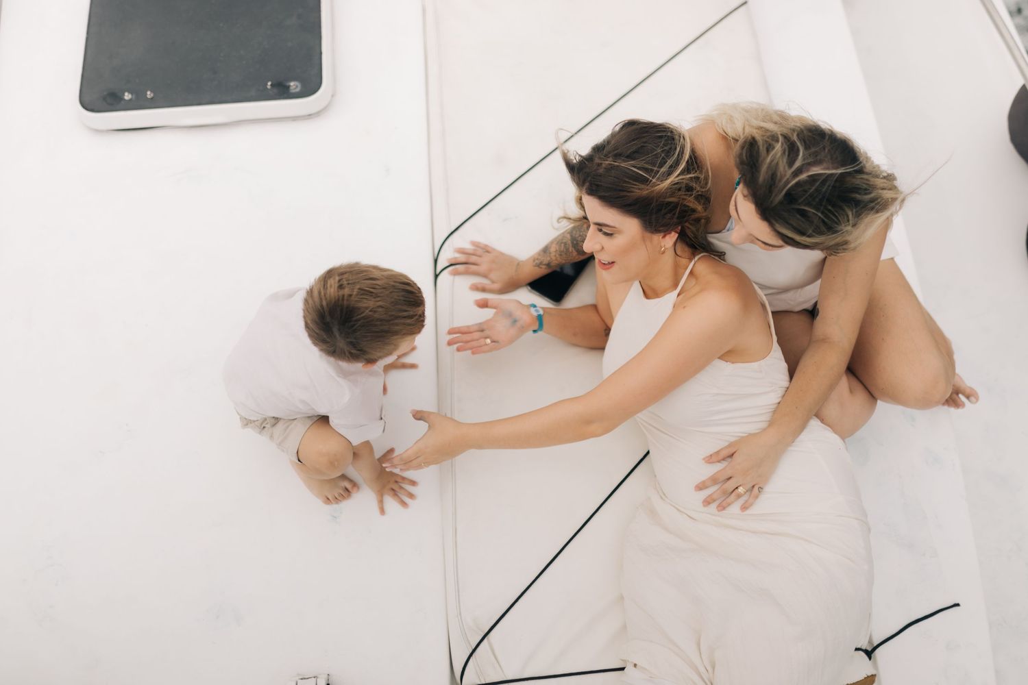 Aerial view of three people lounging on white boat deck.