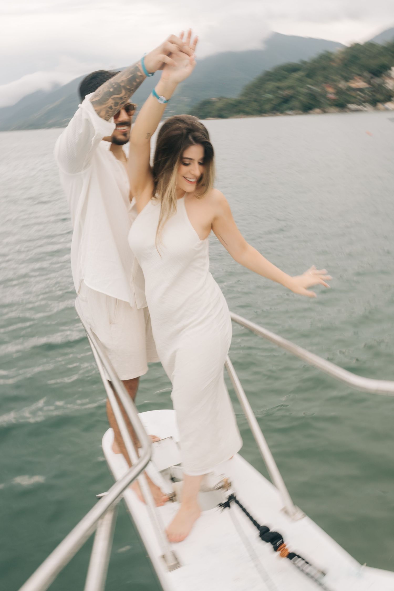 Couple dancing together on the bow of a boat surrounded by mountain scenery.
