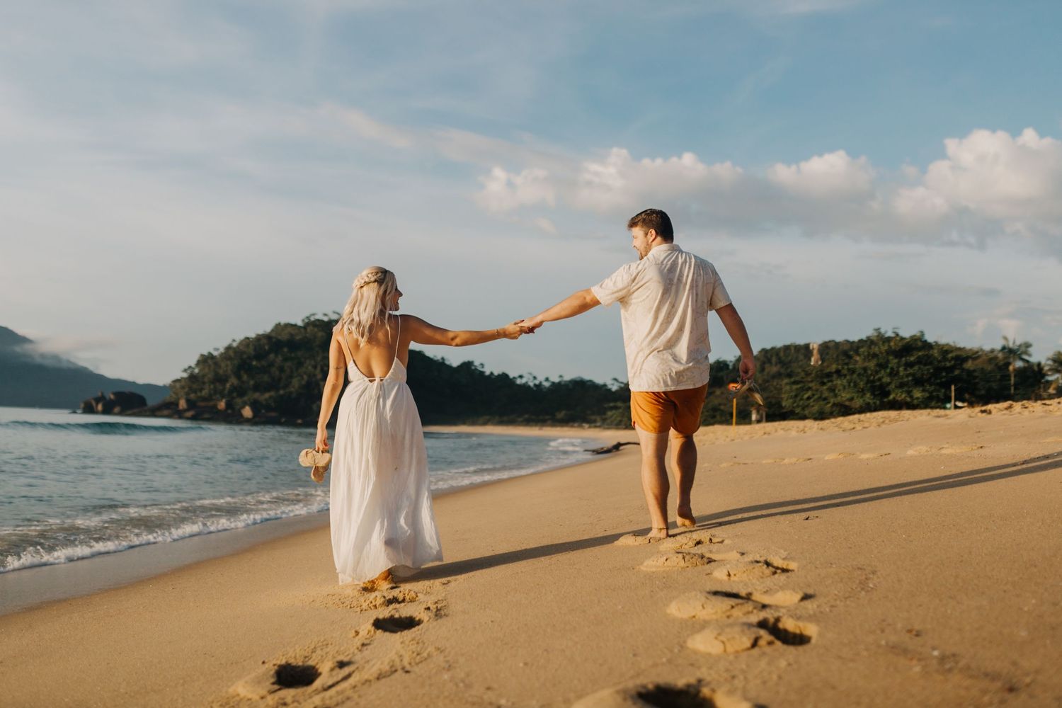 Carefree couple playing and running together on tropical beach with ocean views.