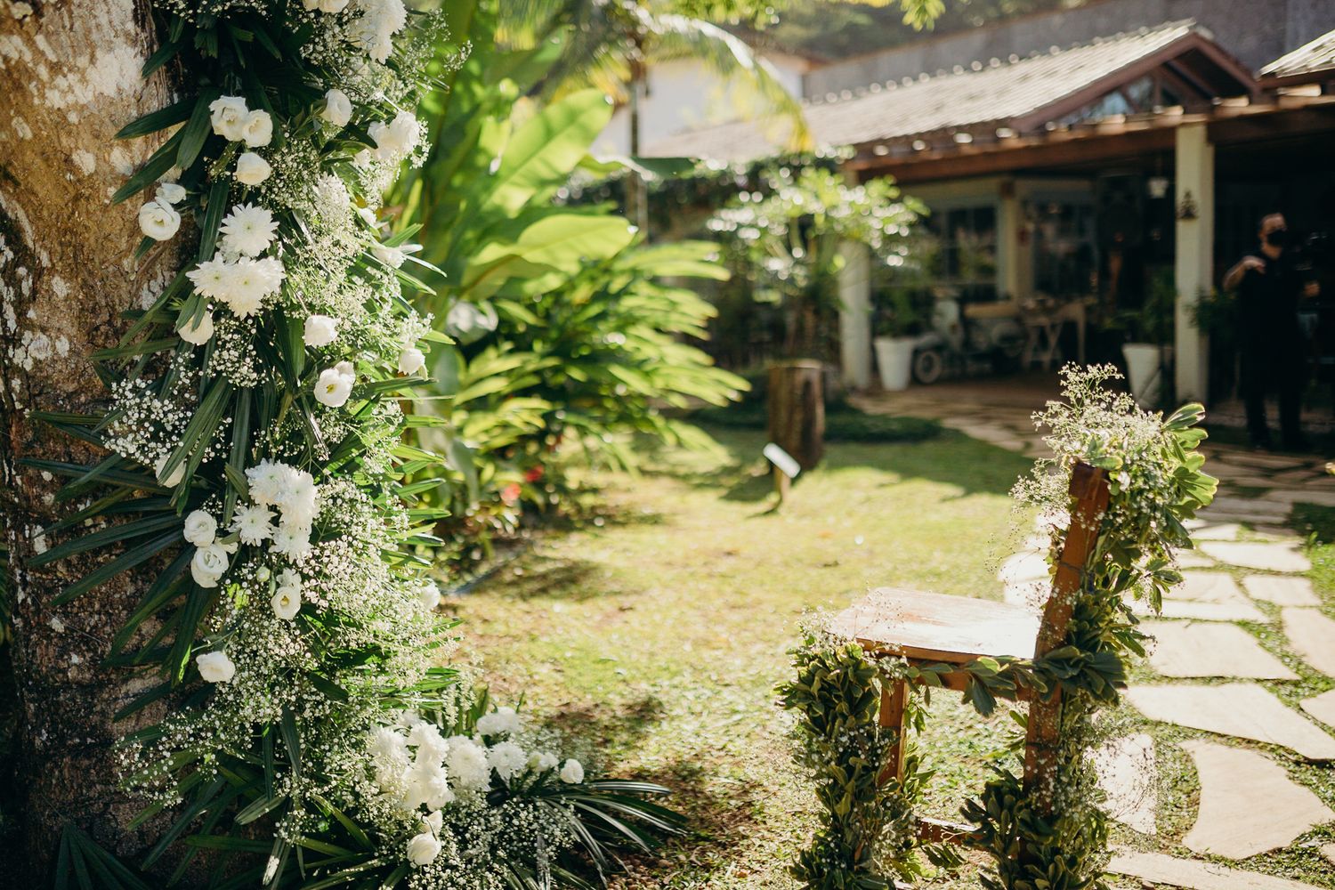A garden wedding ceremony setup with white floral arrangements and natural greenery.