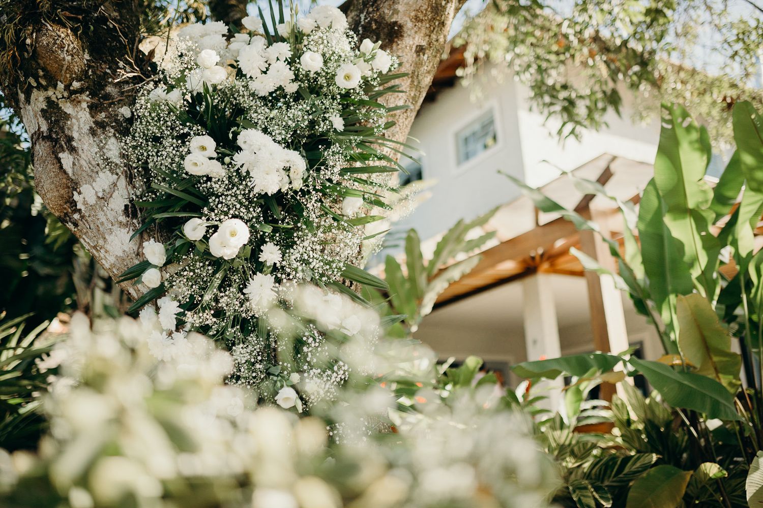White floral arrangements and greenery create an elegant outdoor garden setting for an event.
