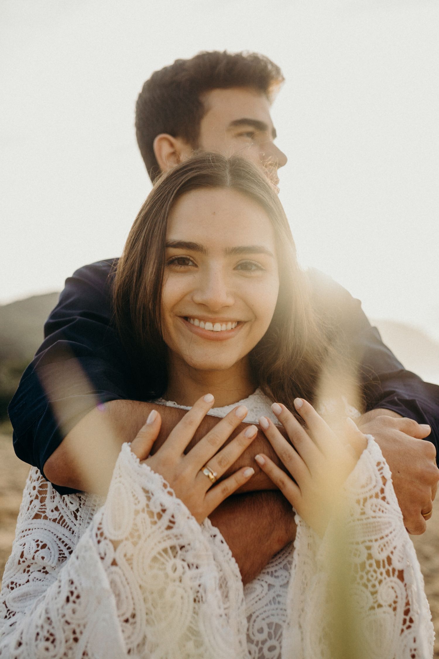 Sunlit portrait of a couple in coordinated outfits sharing an intimate moment outdoors.