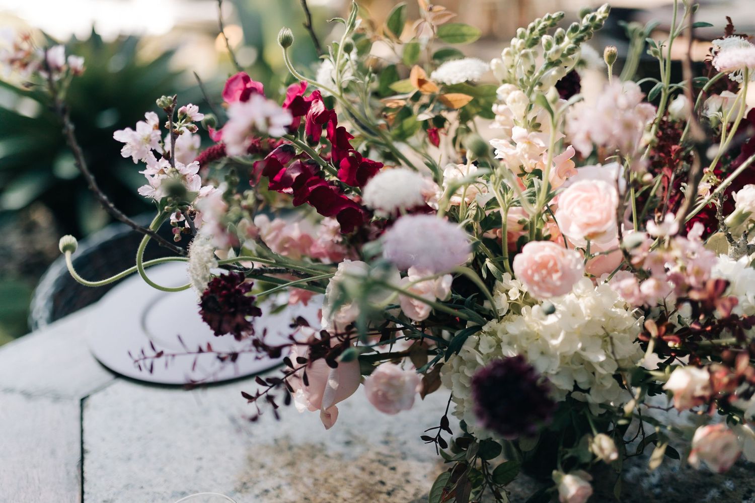 Beautiful floral arrangement with pink and burgundy blooms against light background.