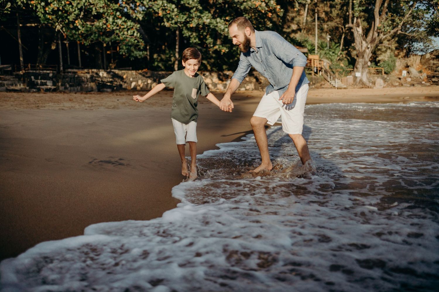 Two people splashing and playing in incoming ocean waves on a sandy beach.