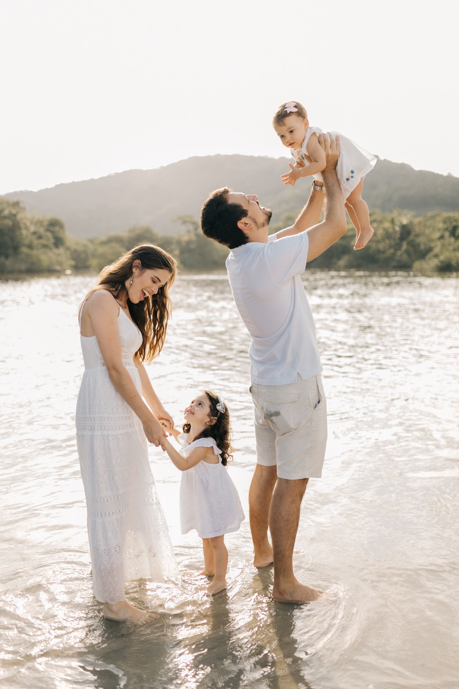 Family enjoying playful moments together in the ocean at sunset.