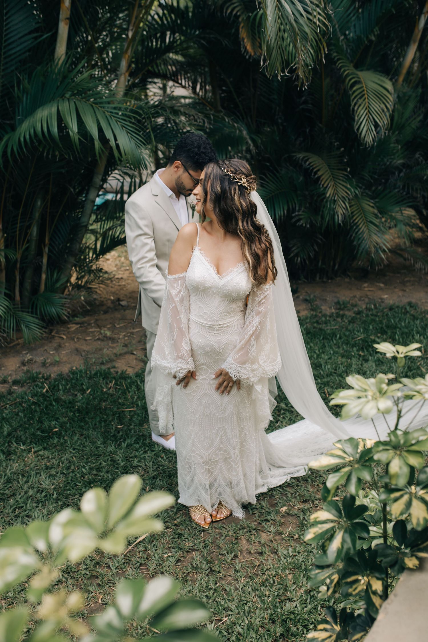 An intimate wedding moment captured in a tropical garden with palm trees and natural lighting.
