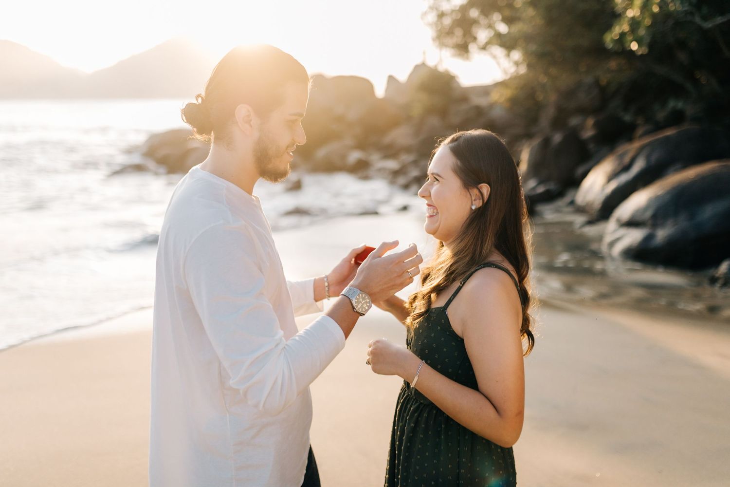 Emotional beach proposal photographed during golden hour with ocean backdrop.
