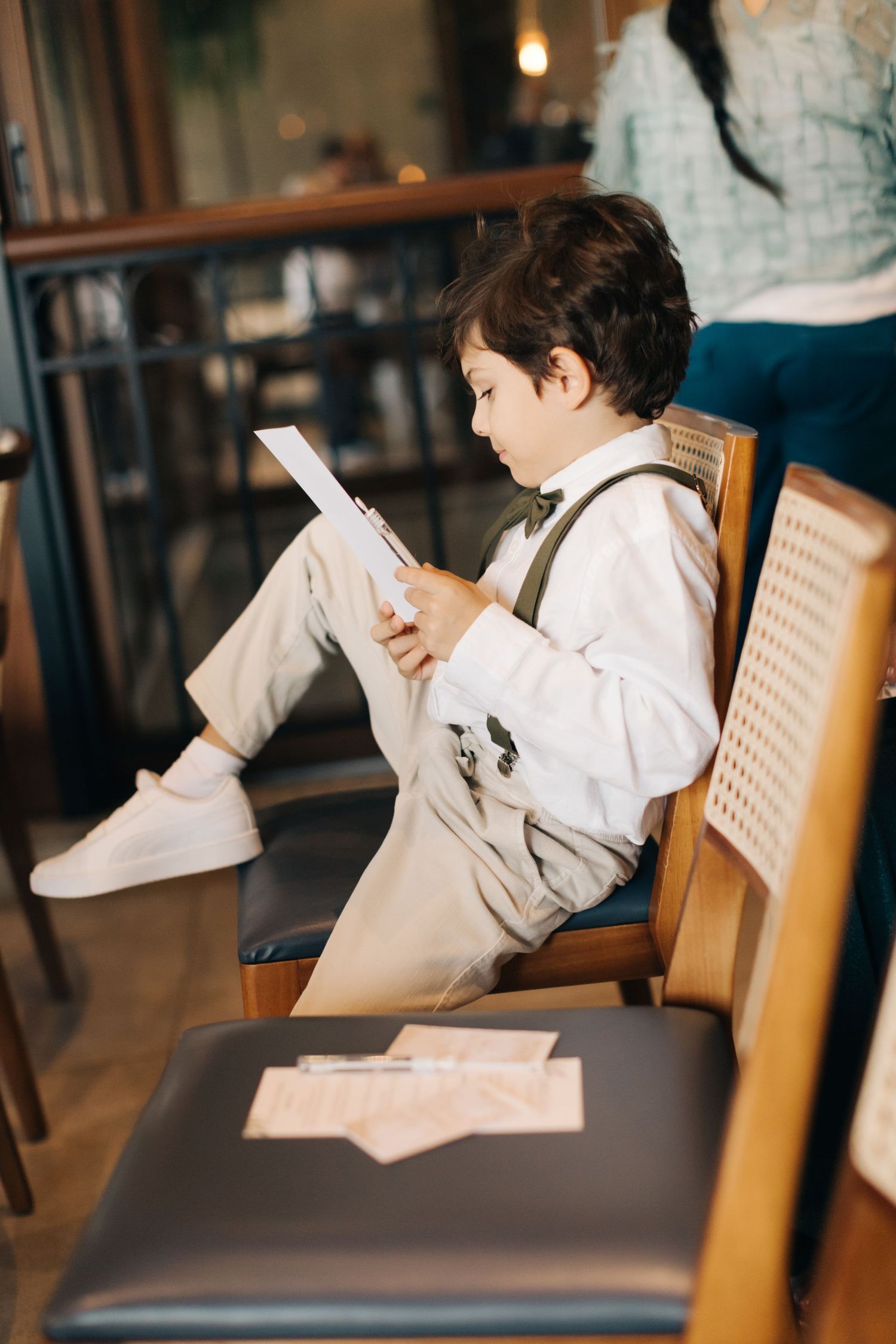 Side view of formally dressed youth reading documents in restaurant setting.