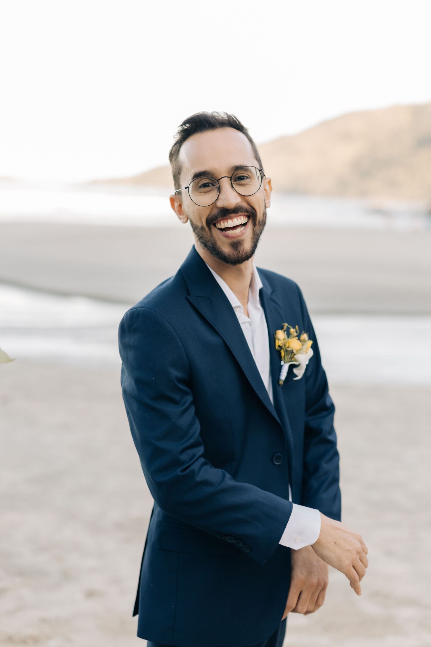 Ocean beach wedding portrait with coastal mountains in background.