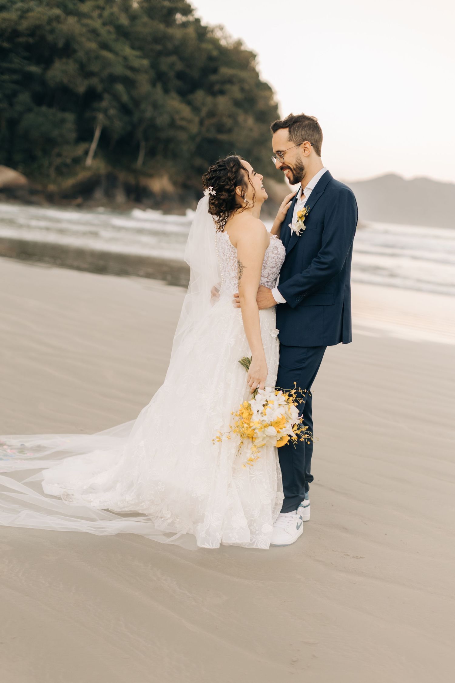 A romantic beach wedding portrait showing the couple standing close together on wet sand.