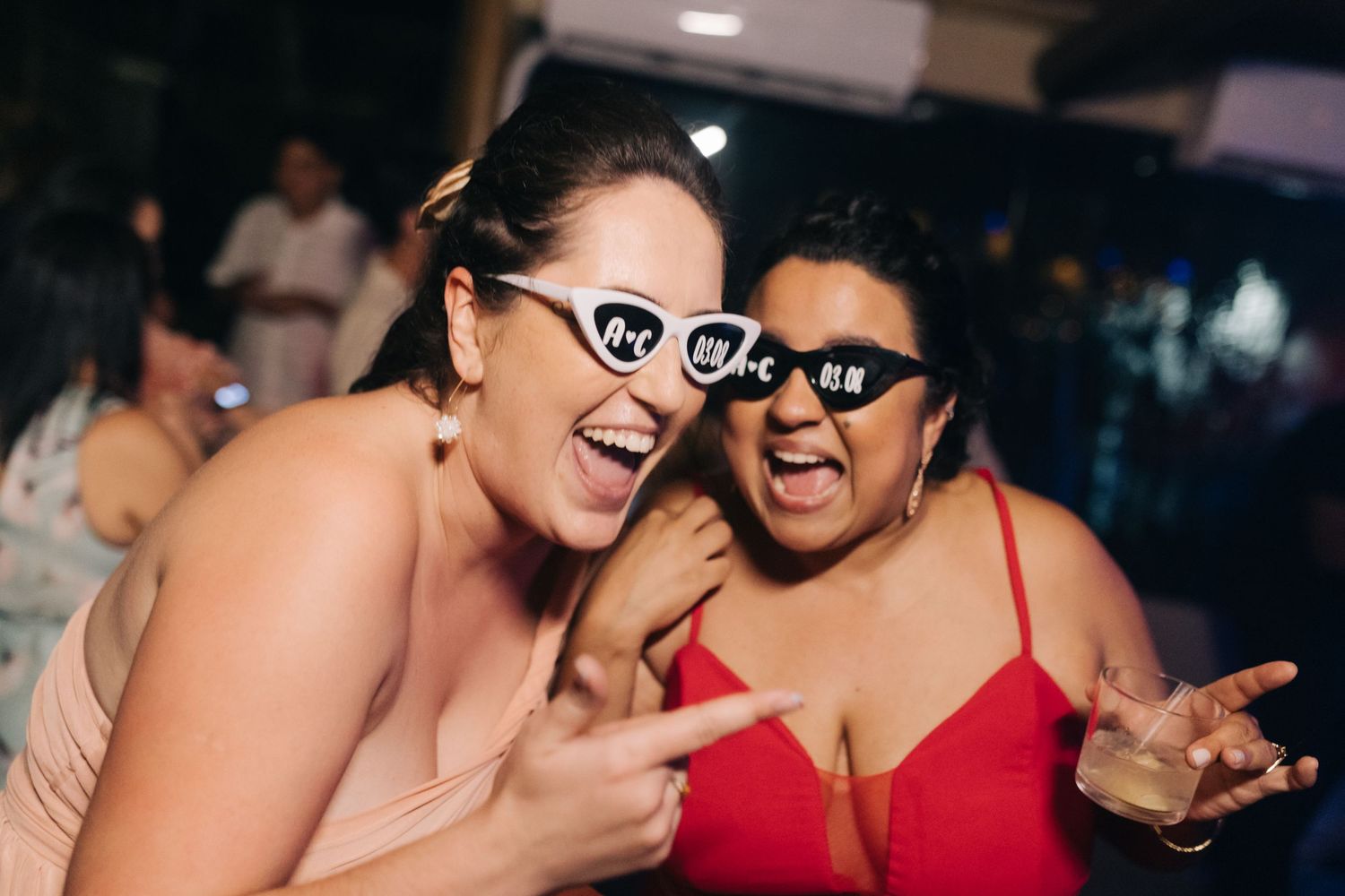 Wedding party guests laughing and dancing together in red dresses.