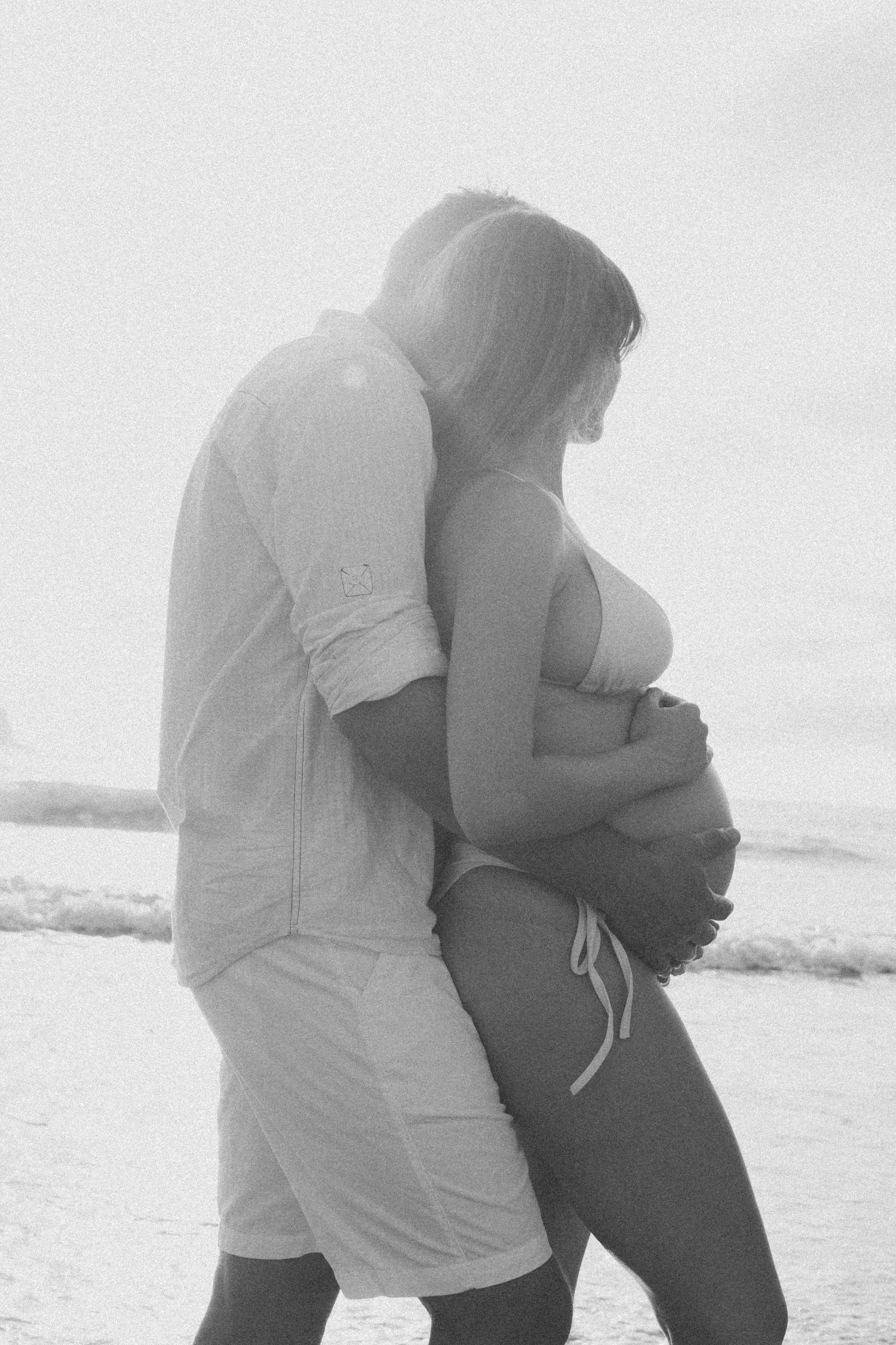 A tender black and white photo of a couple embracing on a misty beach.