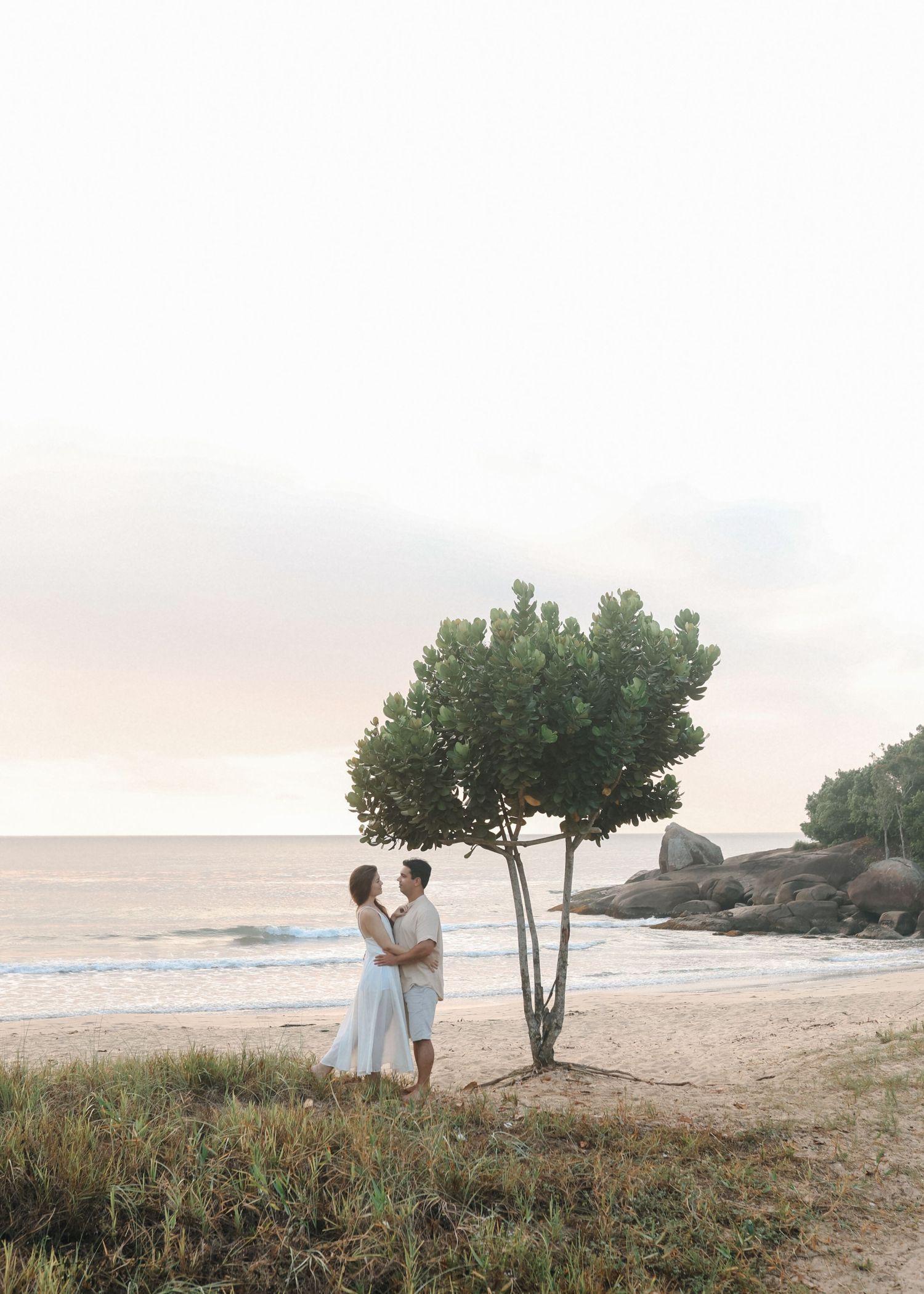 Romantic beach photoshoot featuring couple exploring coastal scenery at dusk.