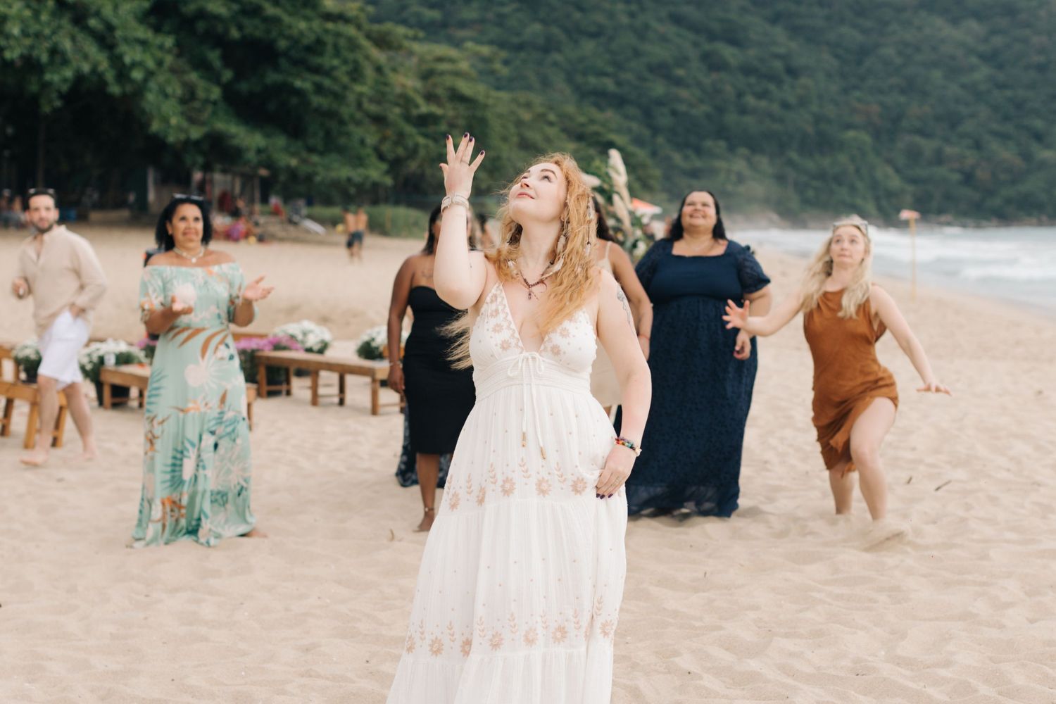 Wedding celebration on beach with people dancing in casual attire.