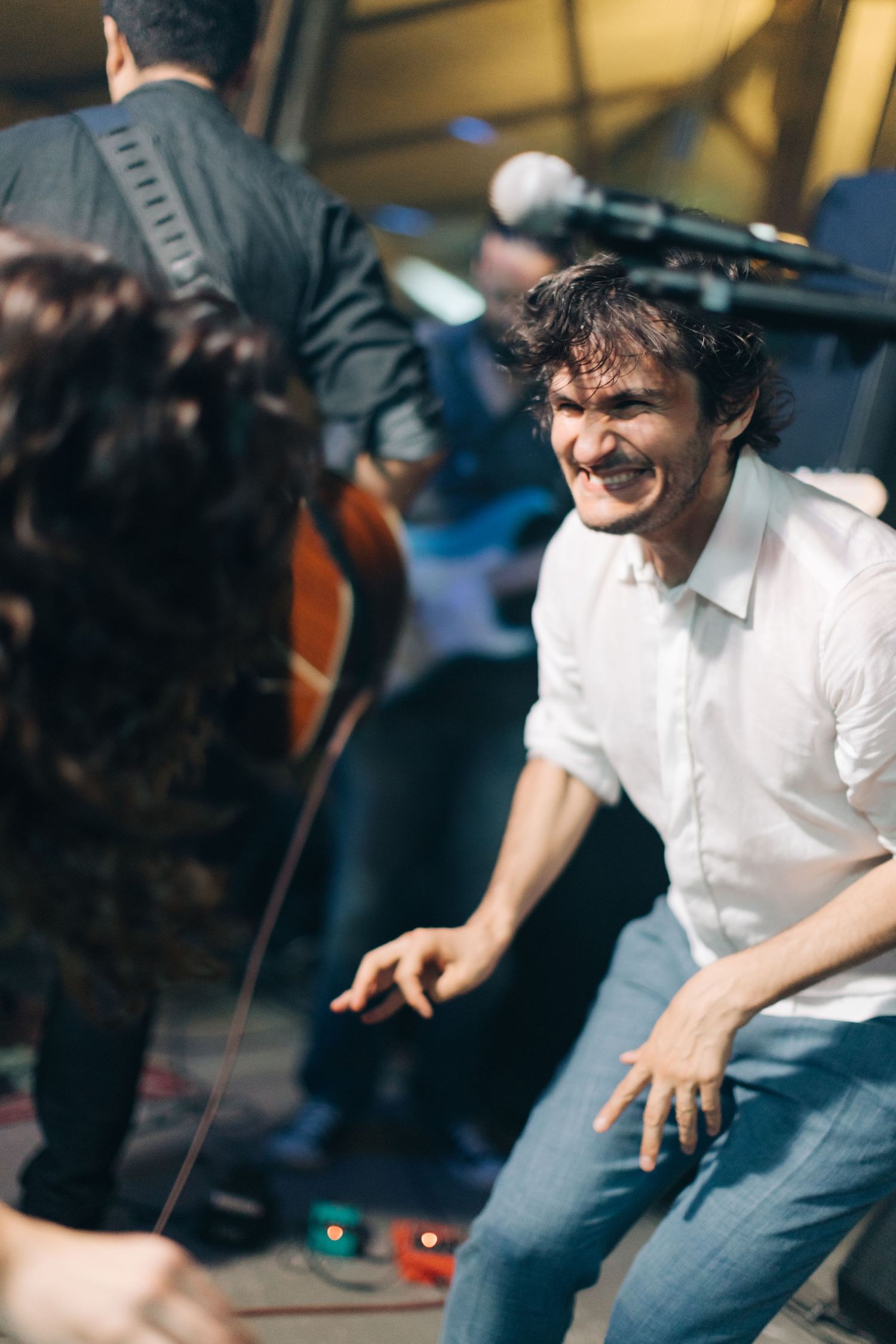 Energetic performer in white shirt dances during live music show.