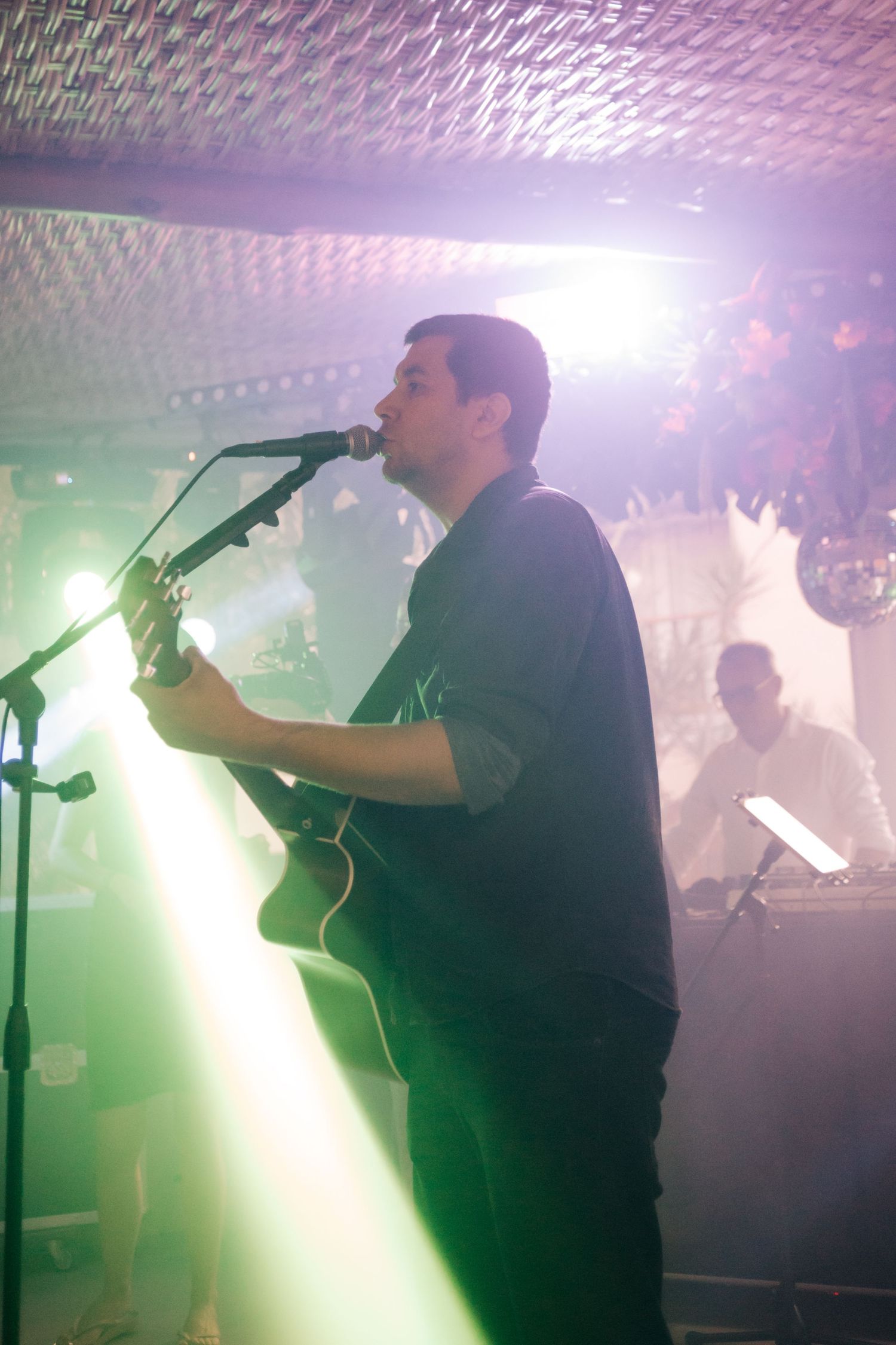 Musicians performing on stage with dramatic green spotlights creating an atmospheric effect.