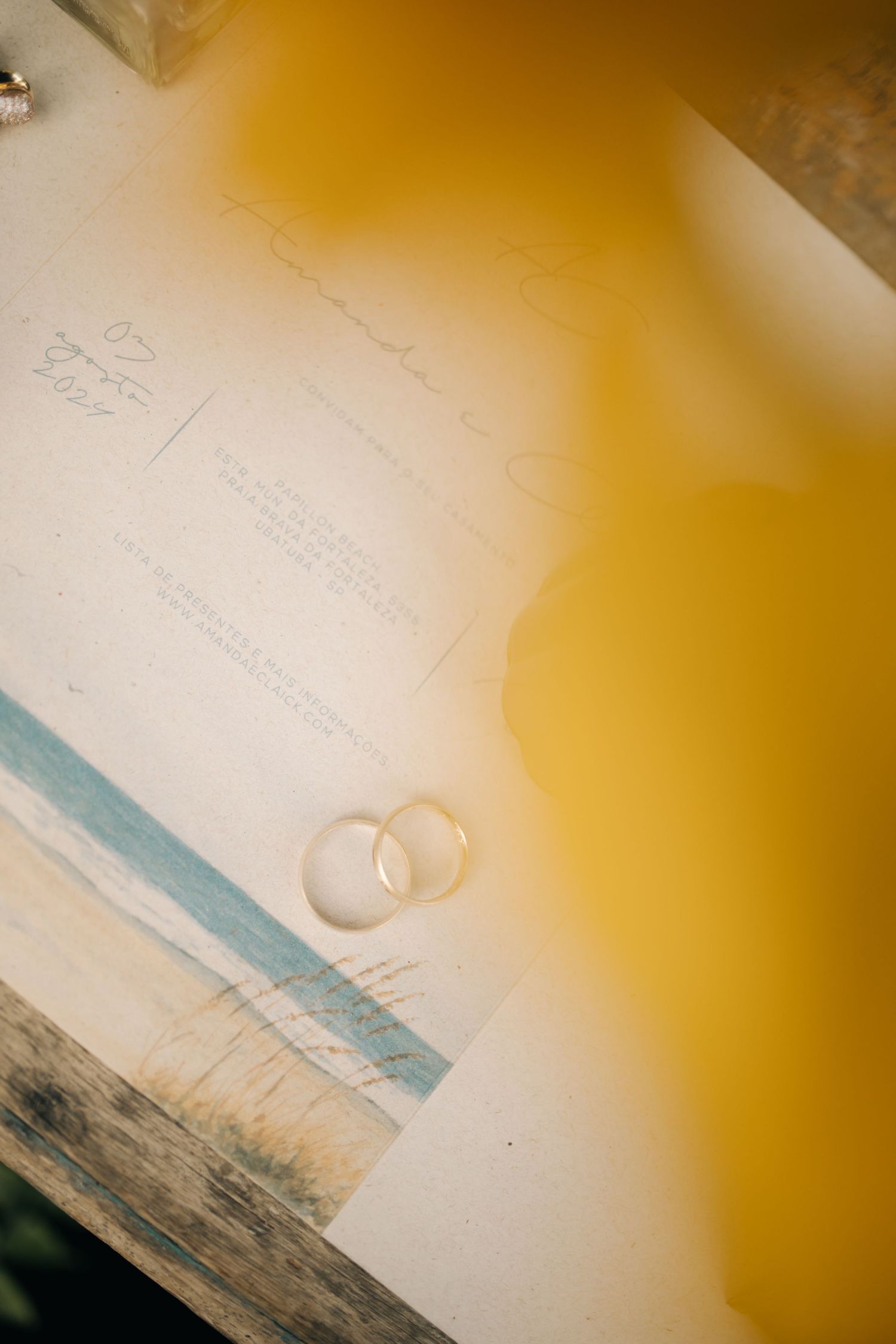 Wedding rings on white paper with yellow light overlay creating artistic effect.