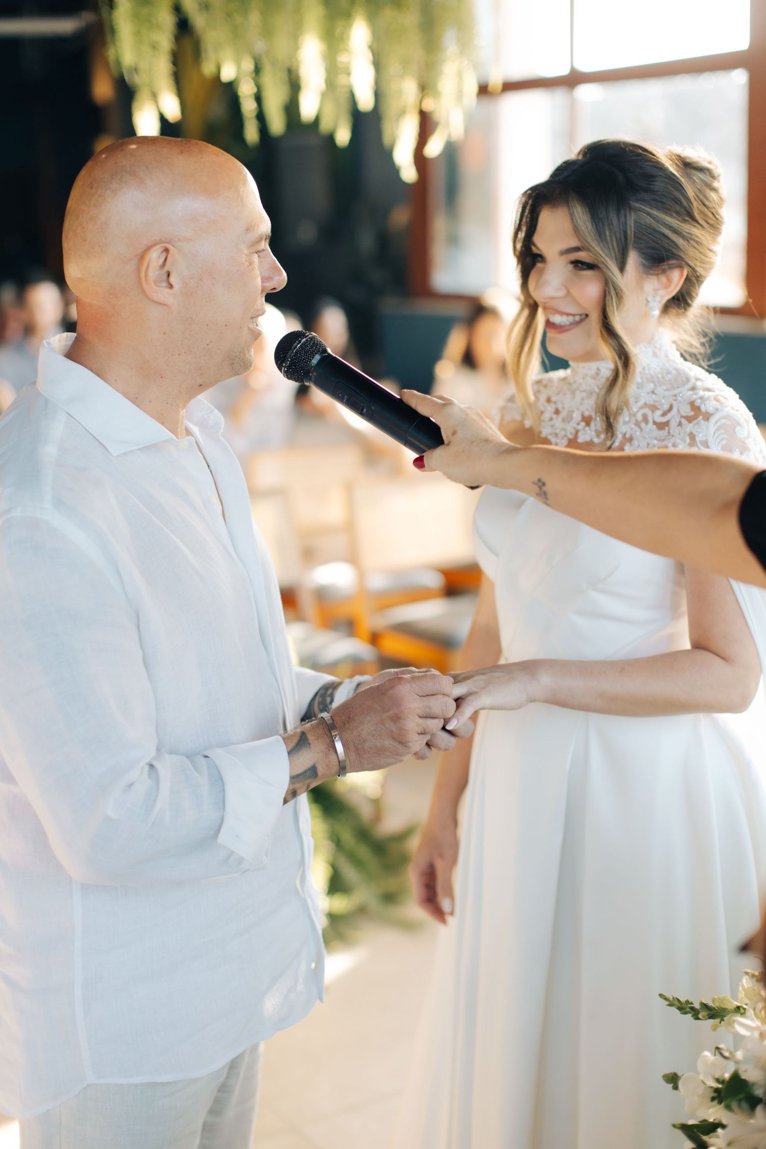 Dancing couple in white formal attire celebrates during wedding reception.