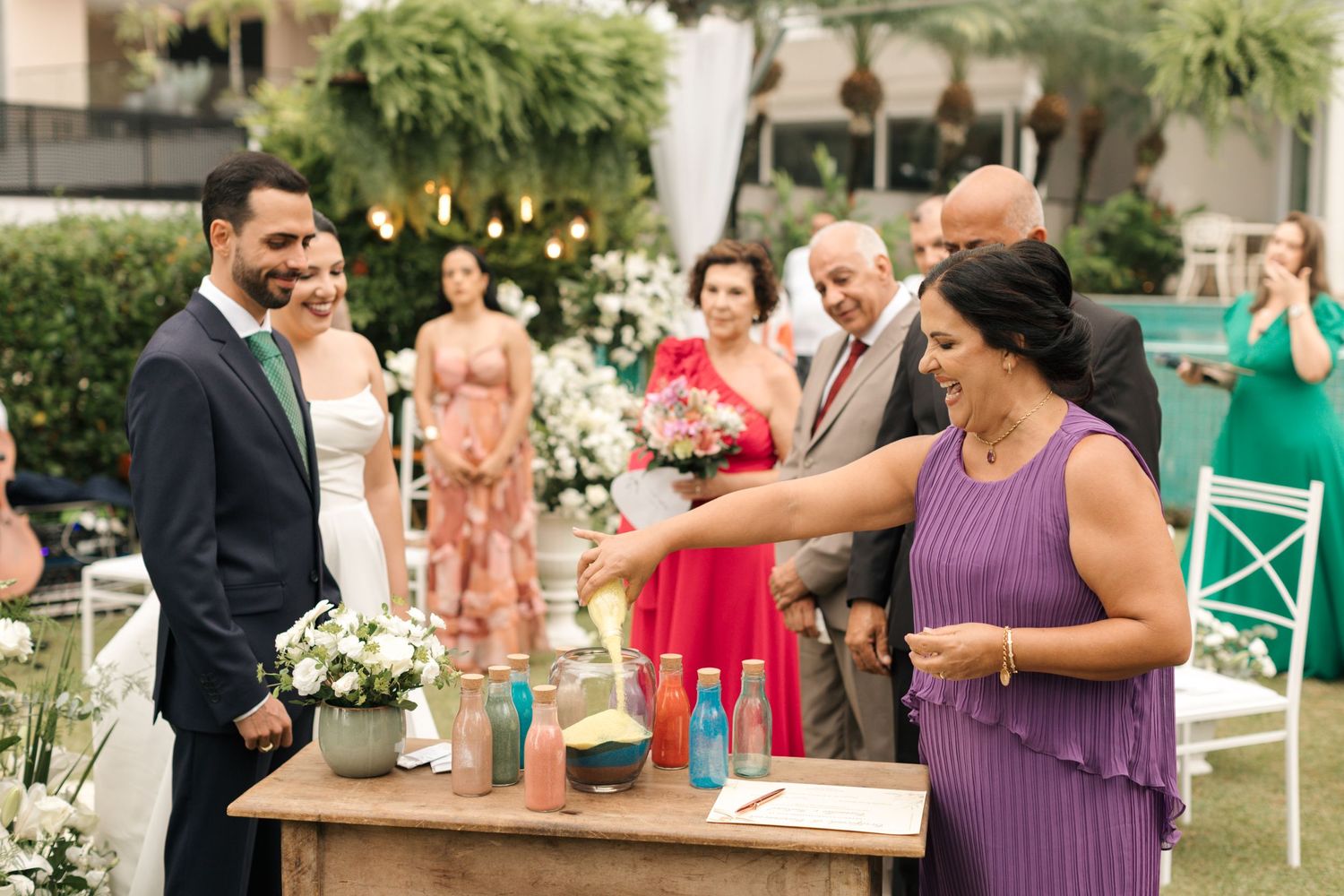 Wedding celebration outdoors with guests participating in a ceremonial drink pouring.