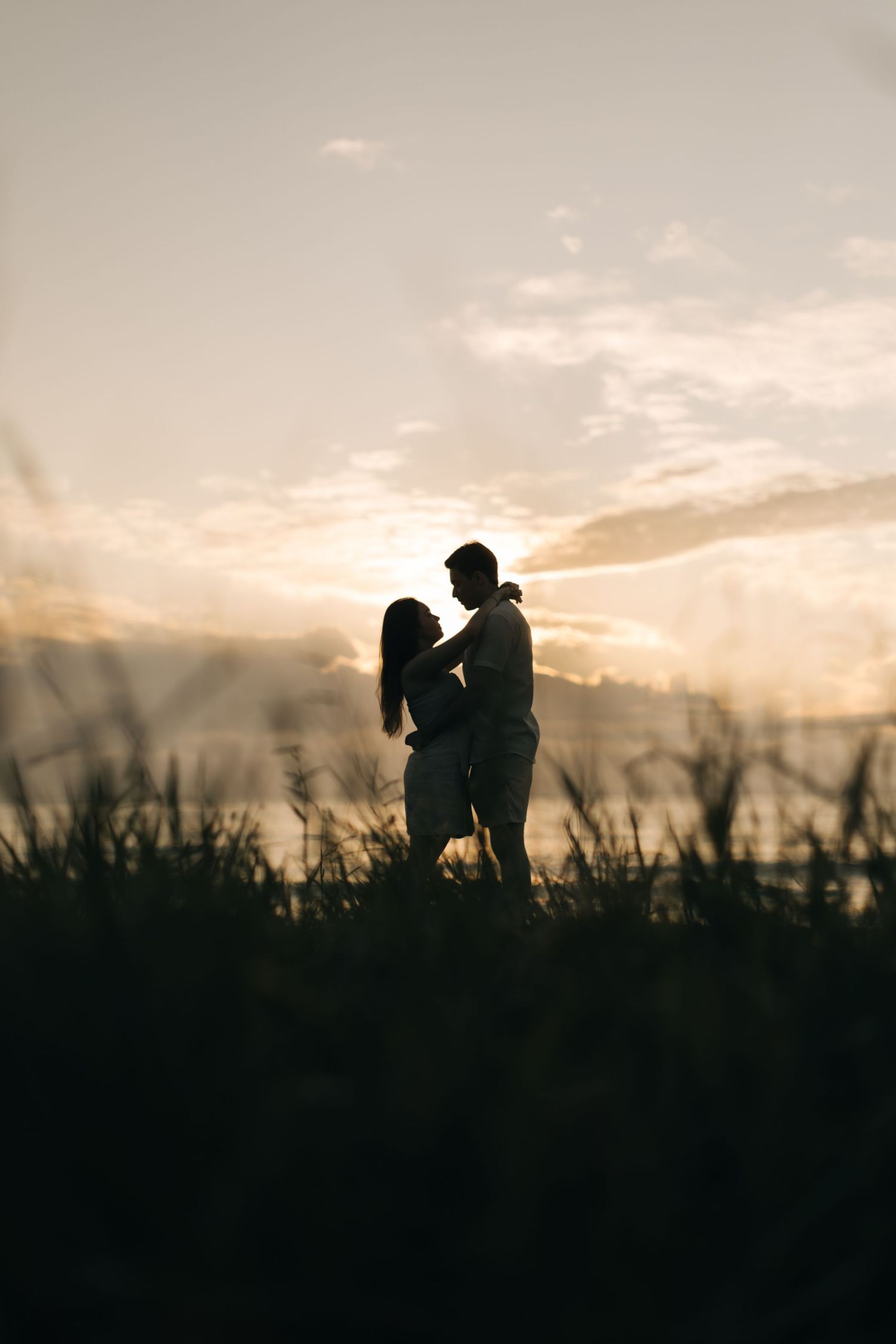 Silhouetted couple standing together against a dramatic sunset sky.