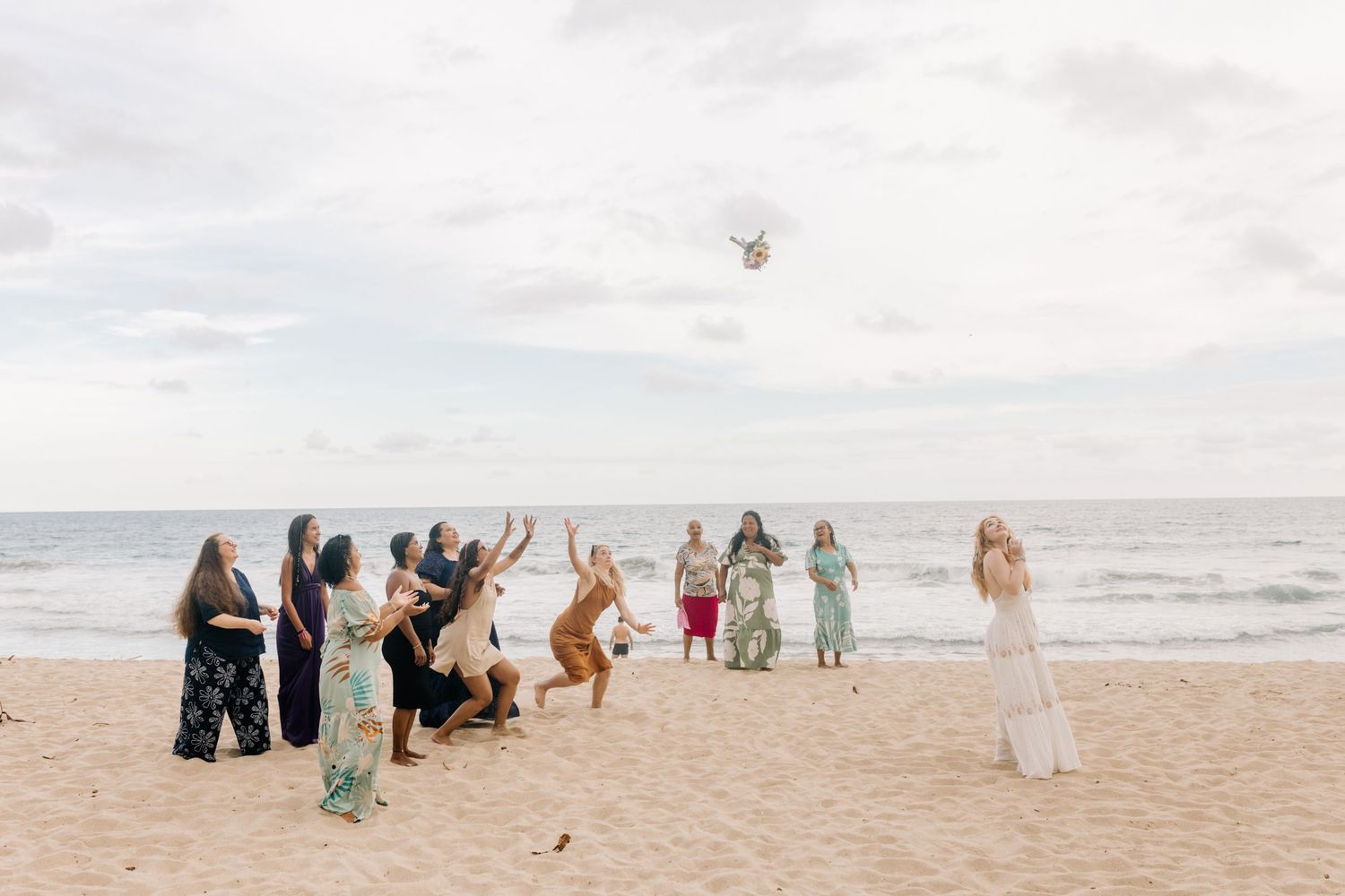 Wedding guests jump joyfully on a beach while a drone captures the moment from above.