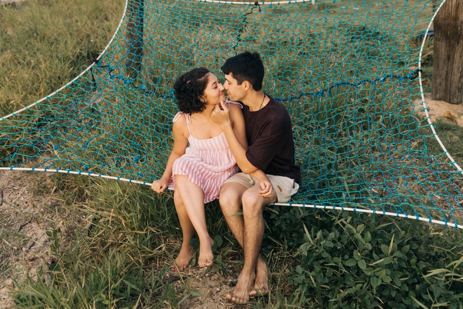 Um casal compartilha um momento romântico sentado em uma rede ao ar livre na natureza.