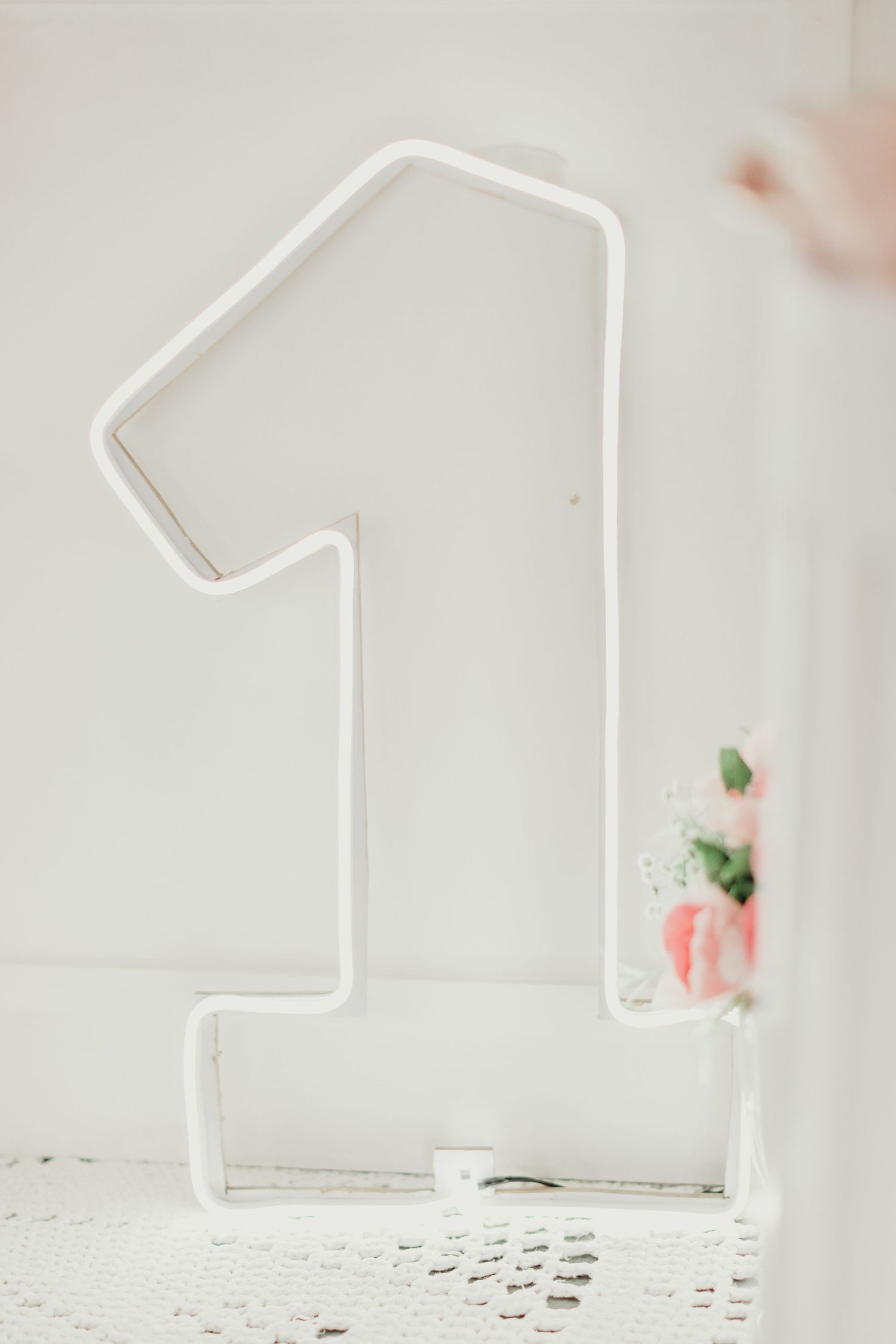 Minimalist white number one display stand against light background.