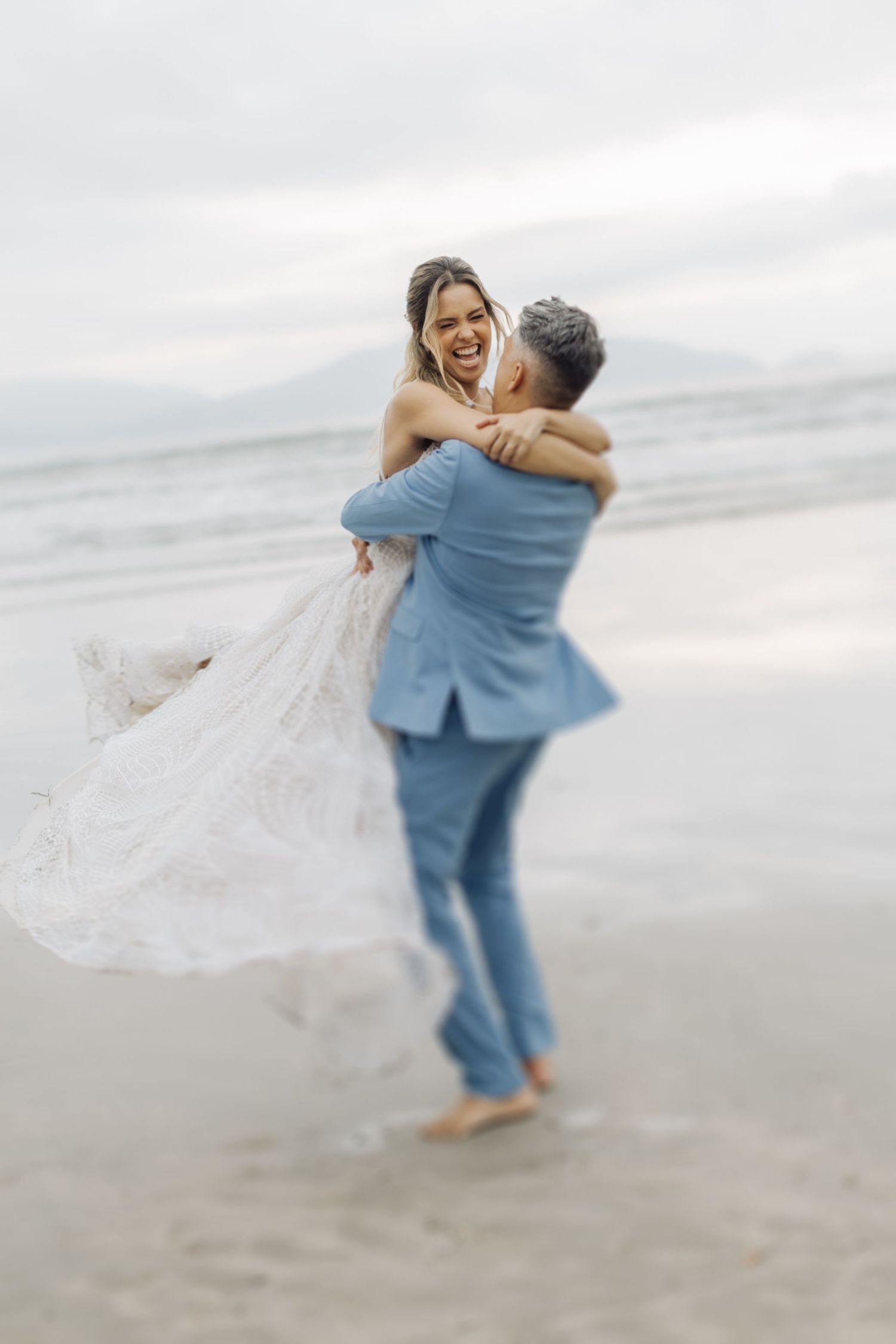 Romantic beach wedding spin with flowing white dress and light blue suit.
