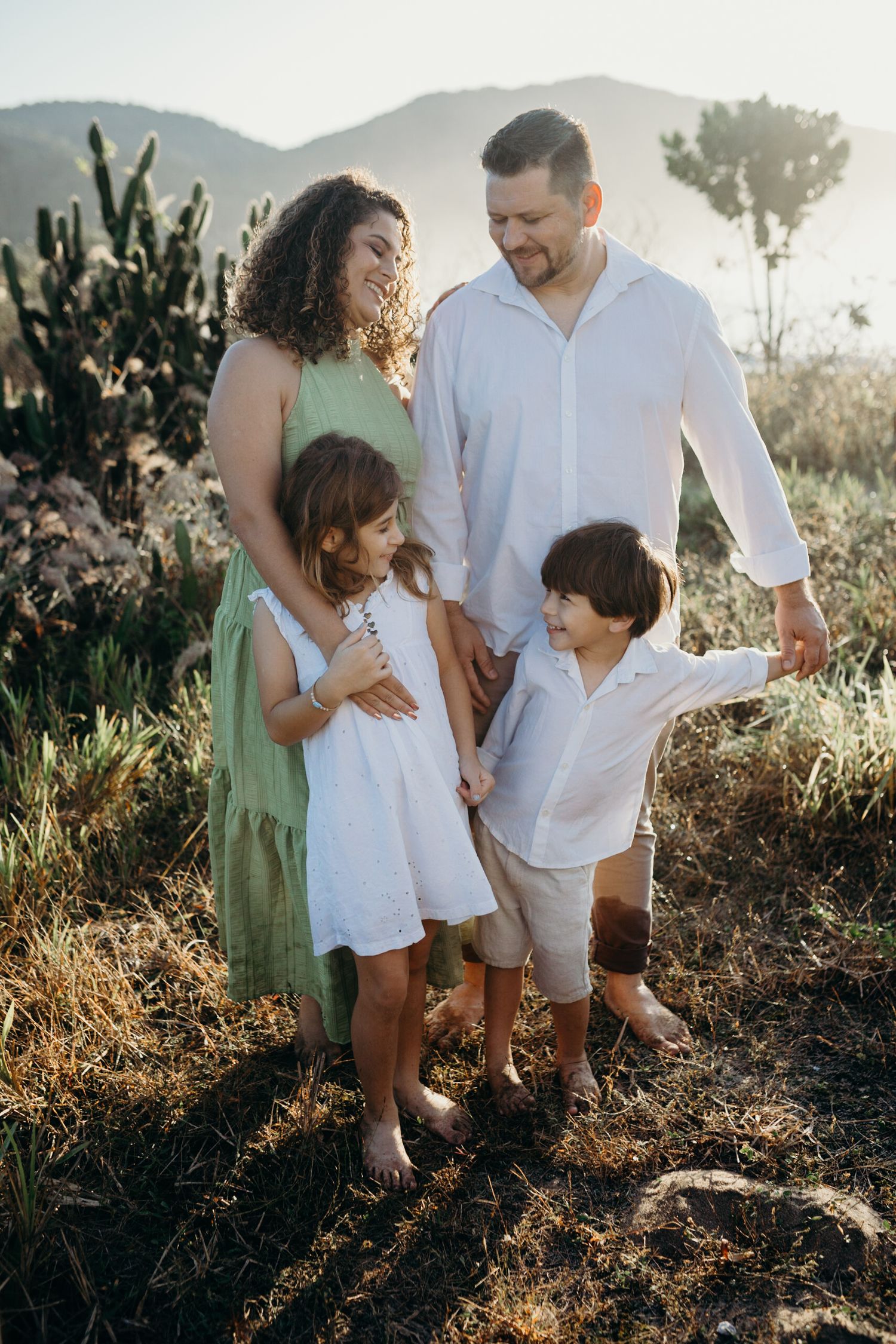 A family stands together on a mountain trail during golden hour with scenic views.