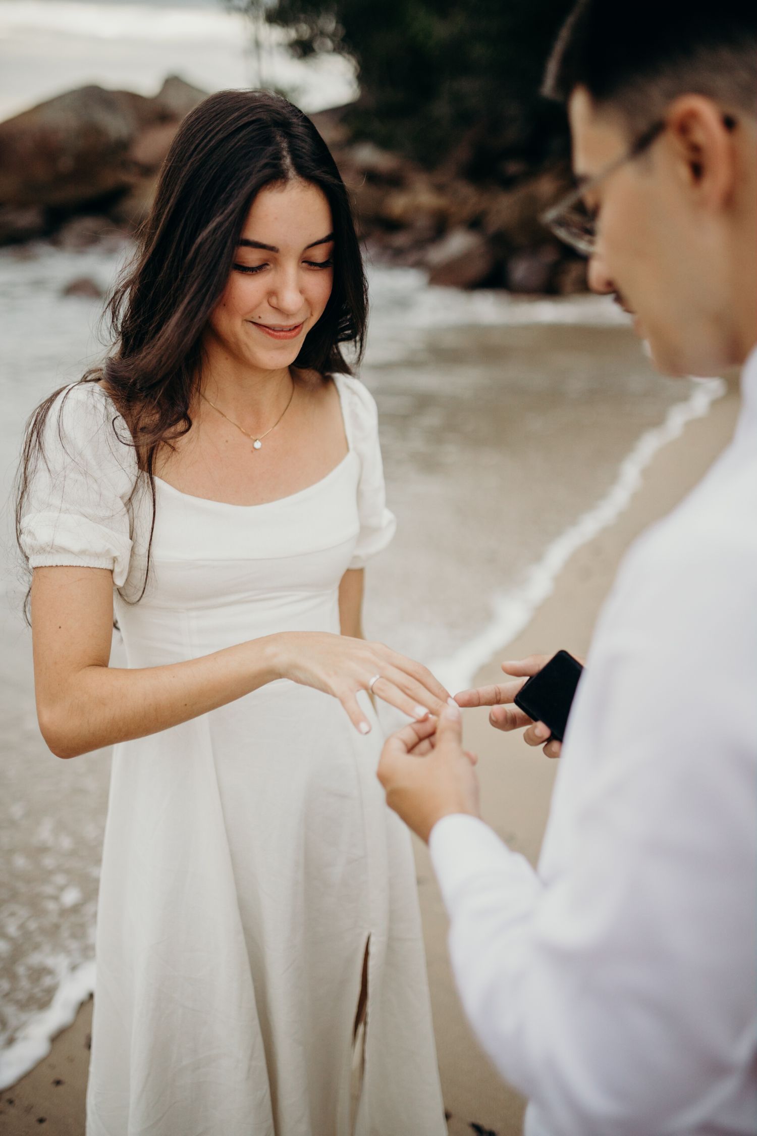 Close-up of engagement ring being presented on beach.