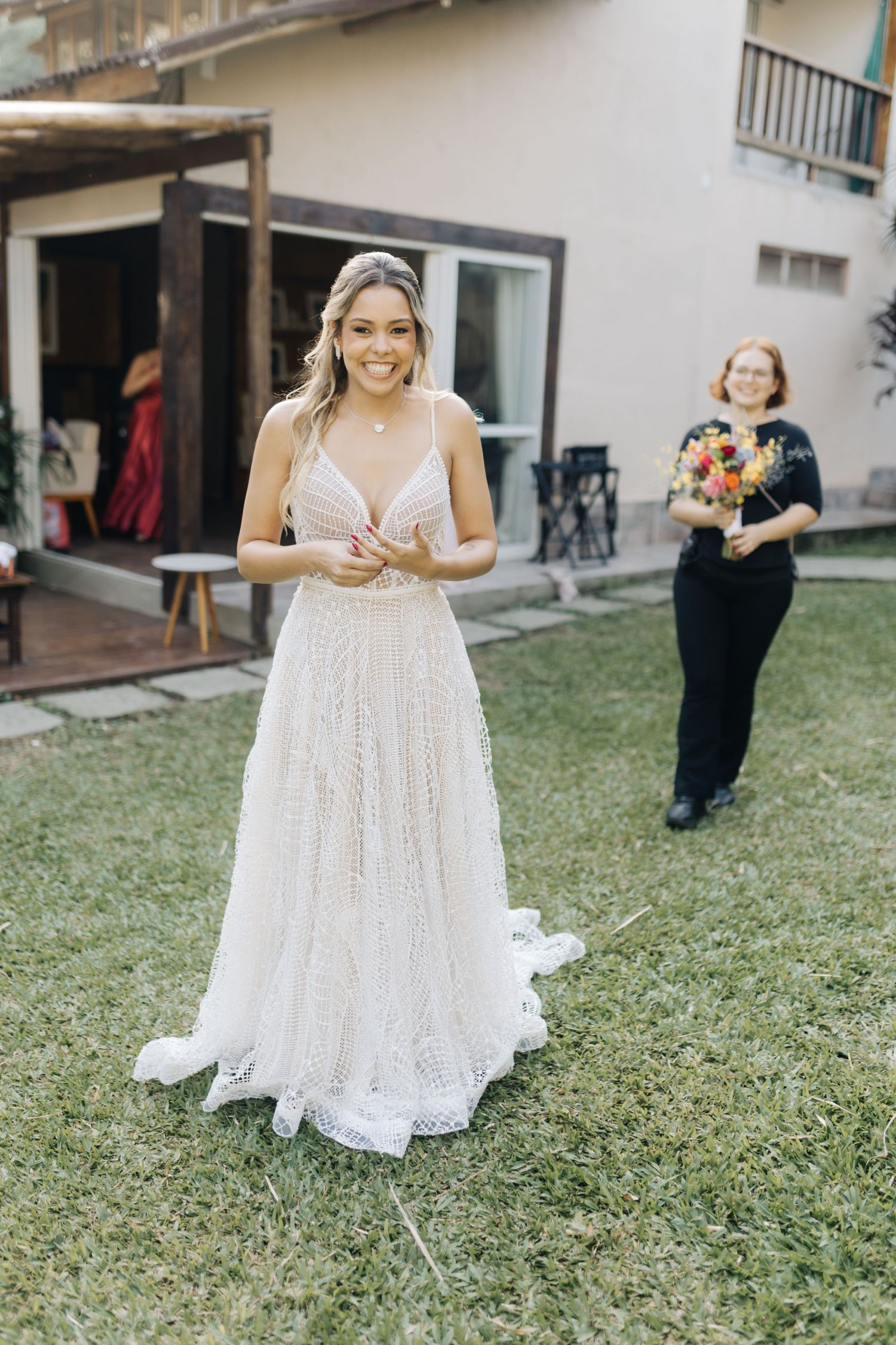 Elegant white wedding dress photographed on a grassy lawn outside a white building.