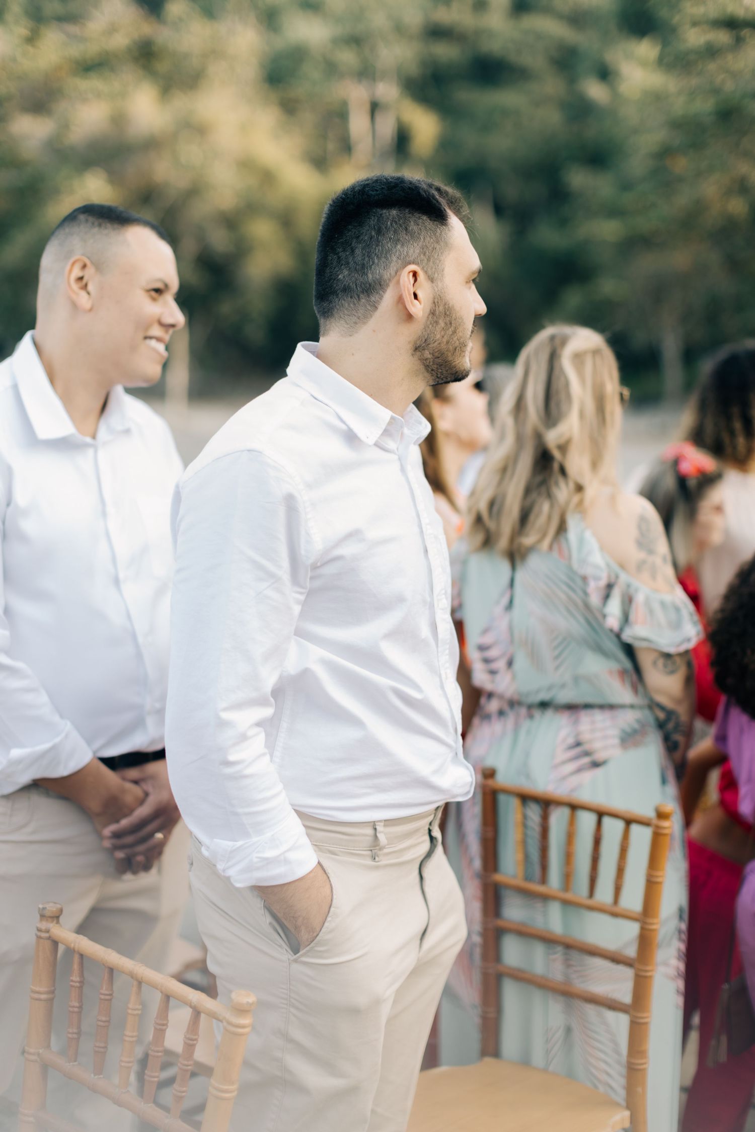 Wedding guests in white shirts and casual attire gather at an outdoor celebration.