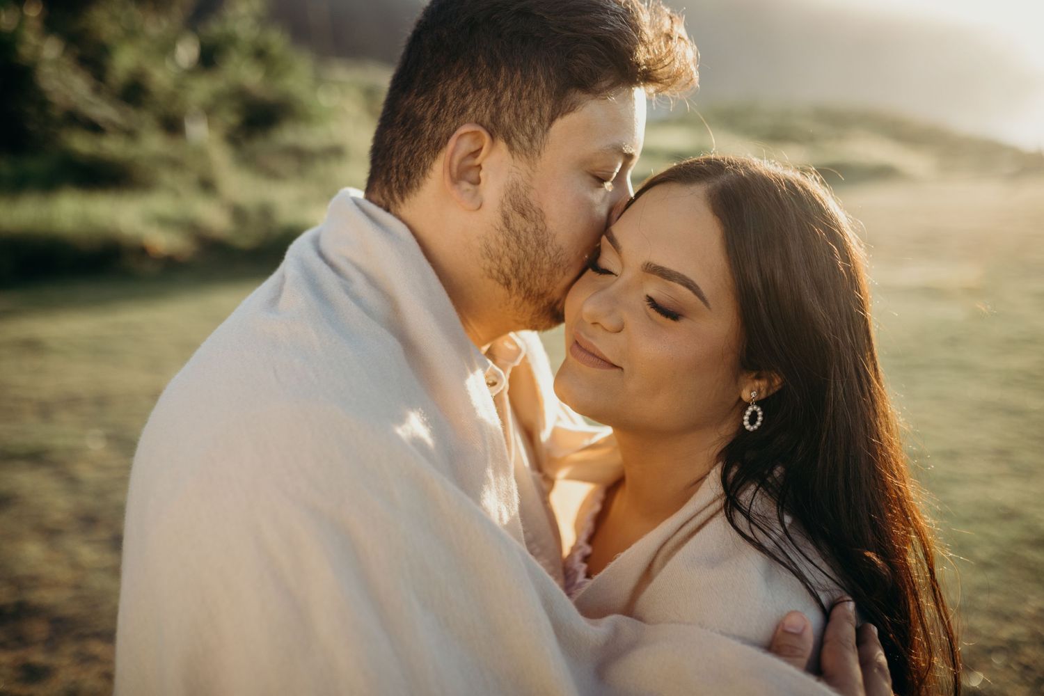 Close-up romantic moment captured in golden hour lighting with mountain backdrop.