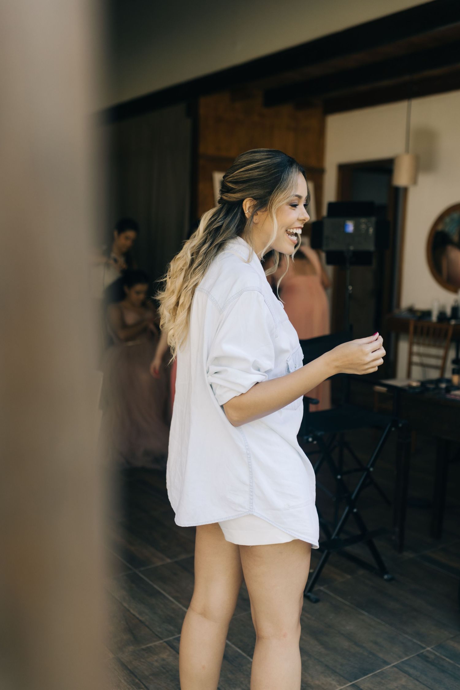 A person in an oversized white shirt laughs while walking through an indoor space.