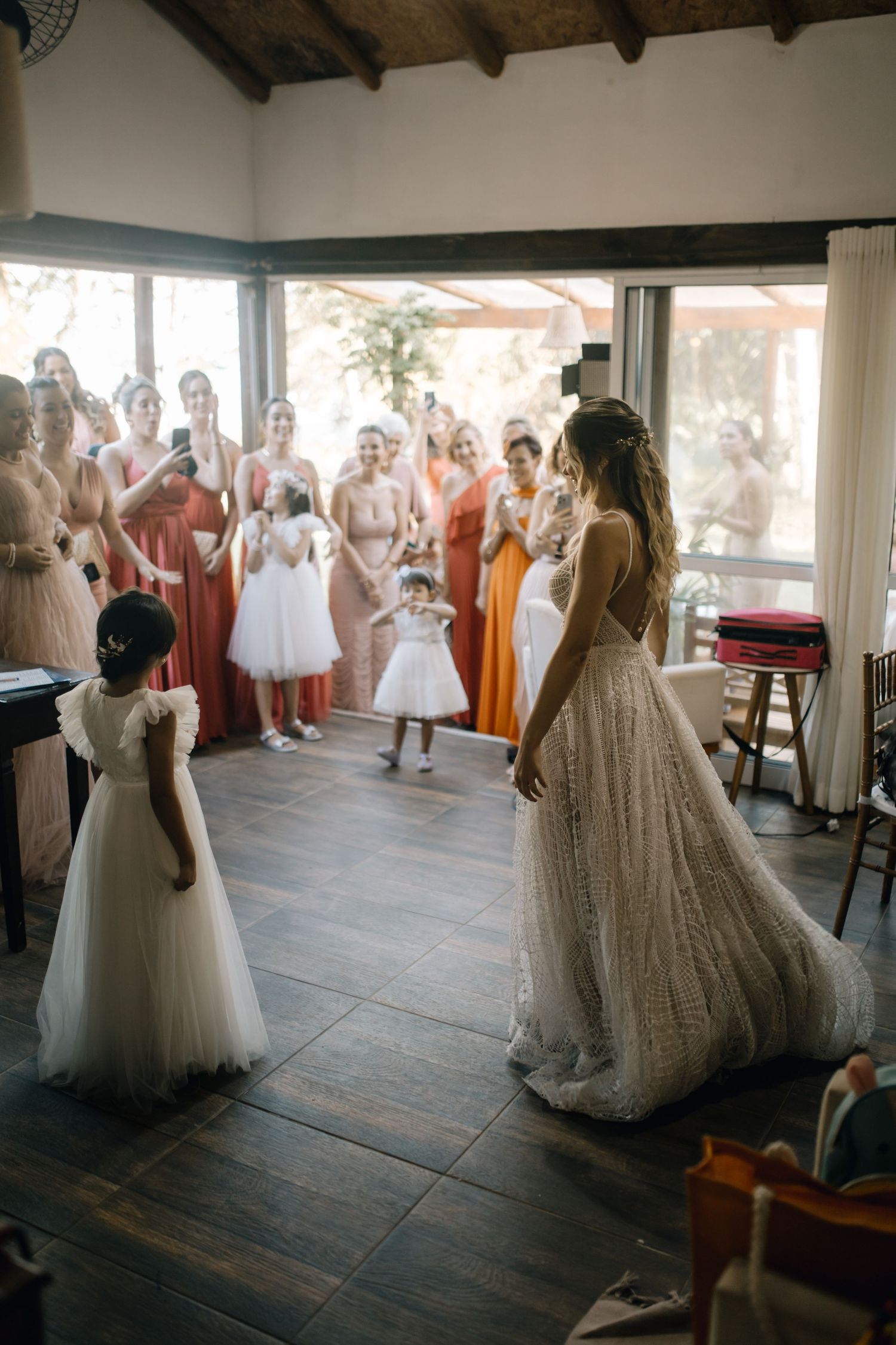Wedding party stands together in a rustic venue with exposed wooden beams and large windows.
